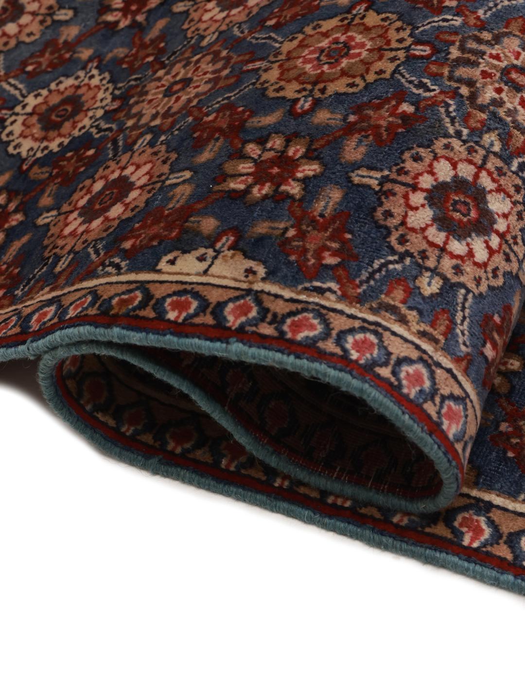 Hand-knotted Sarouk rug from the Middle East featuring a blue field with floral motifs.