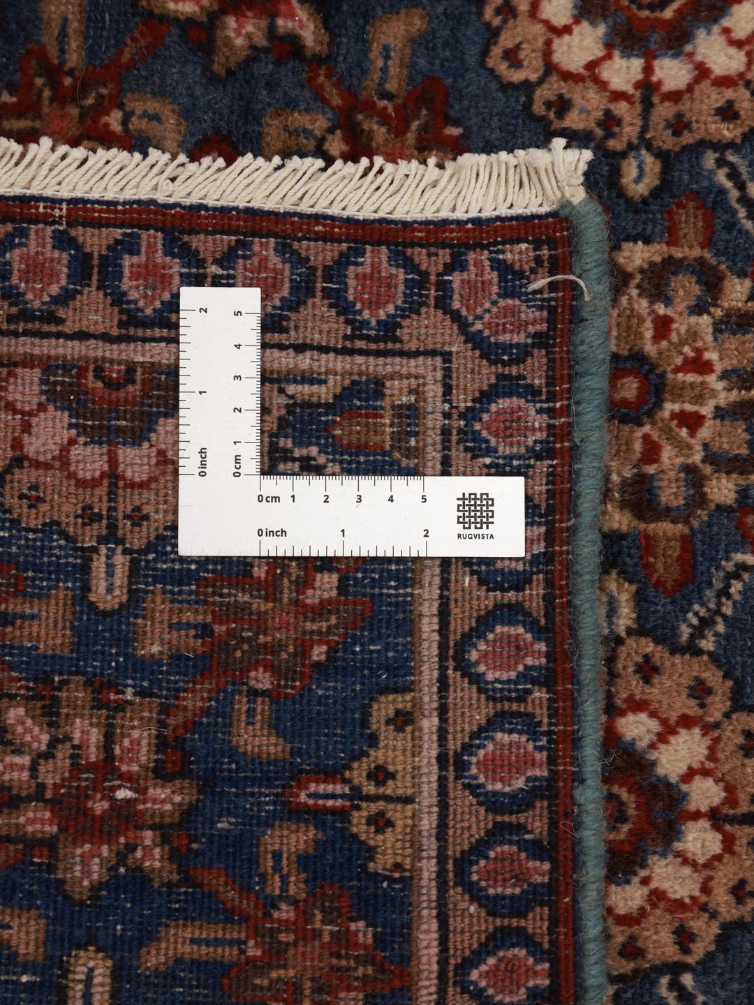 Hand-knotted Sarouk rug from the Middle East featuring a blue field with floral motifs.