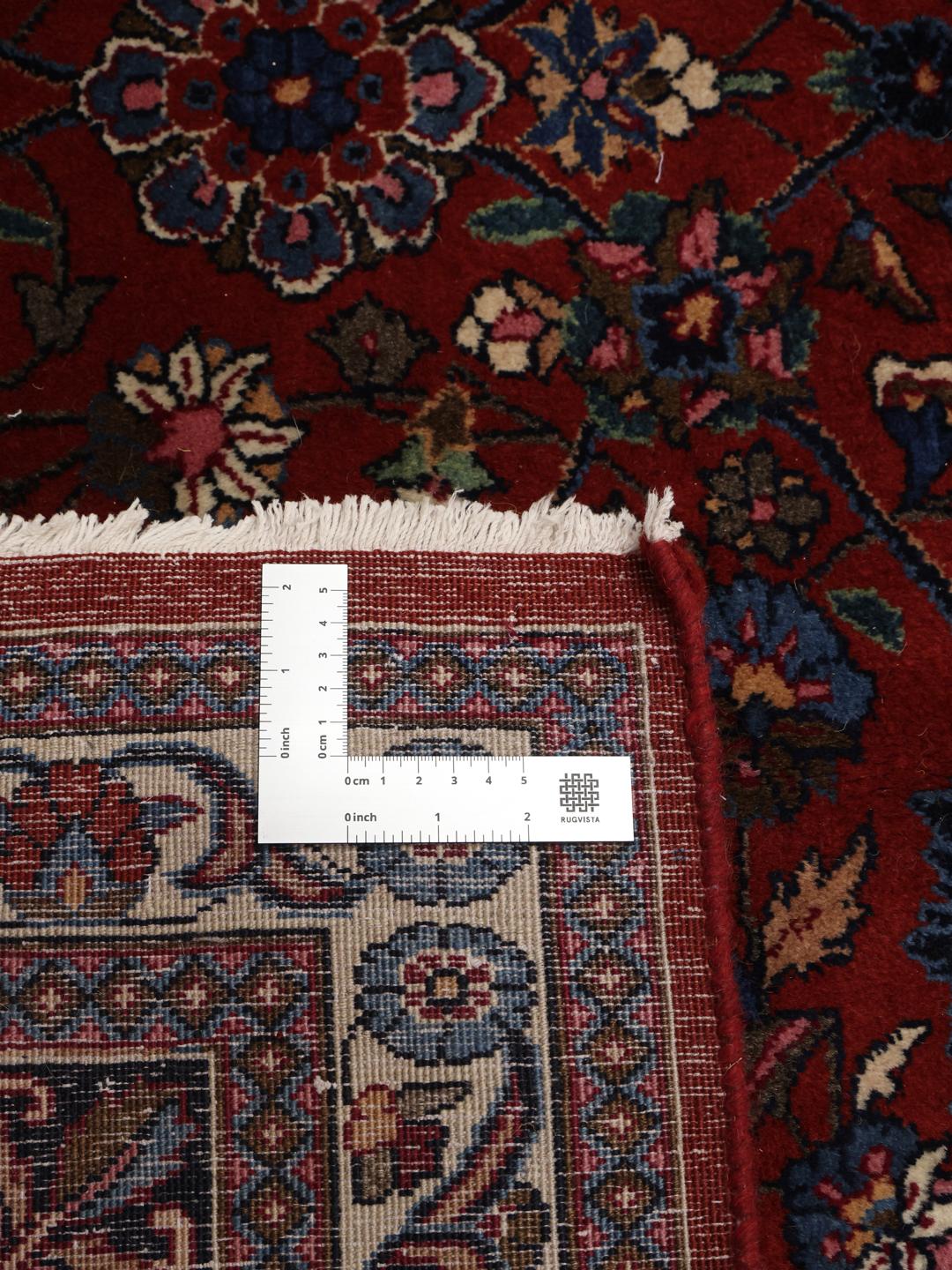 Et stort, håndknyttet Mashad-tæppe fra Mellemøsten med en dybrød bund og indviklede blomstermønstre.