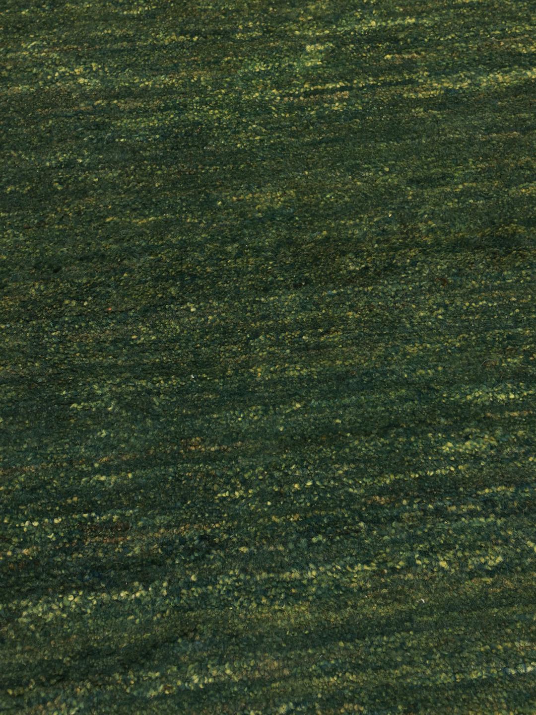A hand-knotted Gabbeh rug from the Middle East in a deep, variegated dark-green colour.