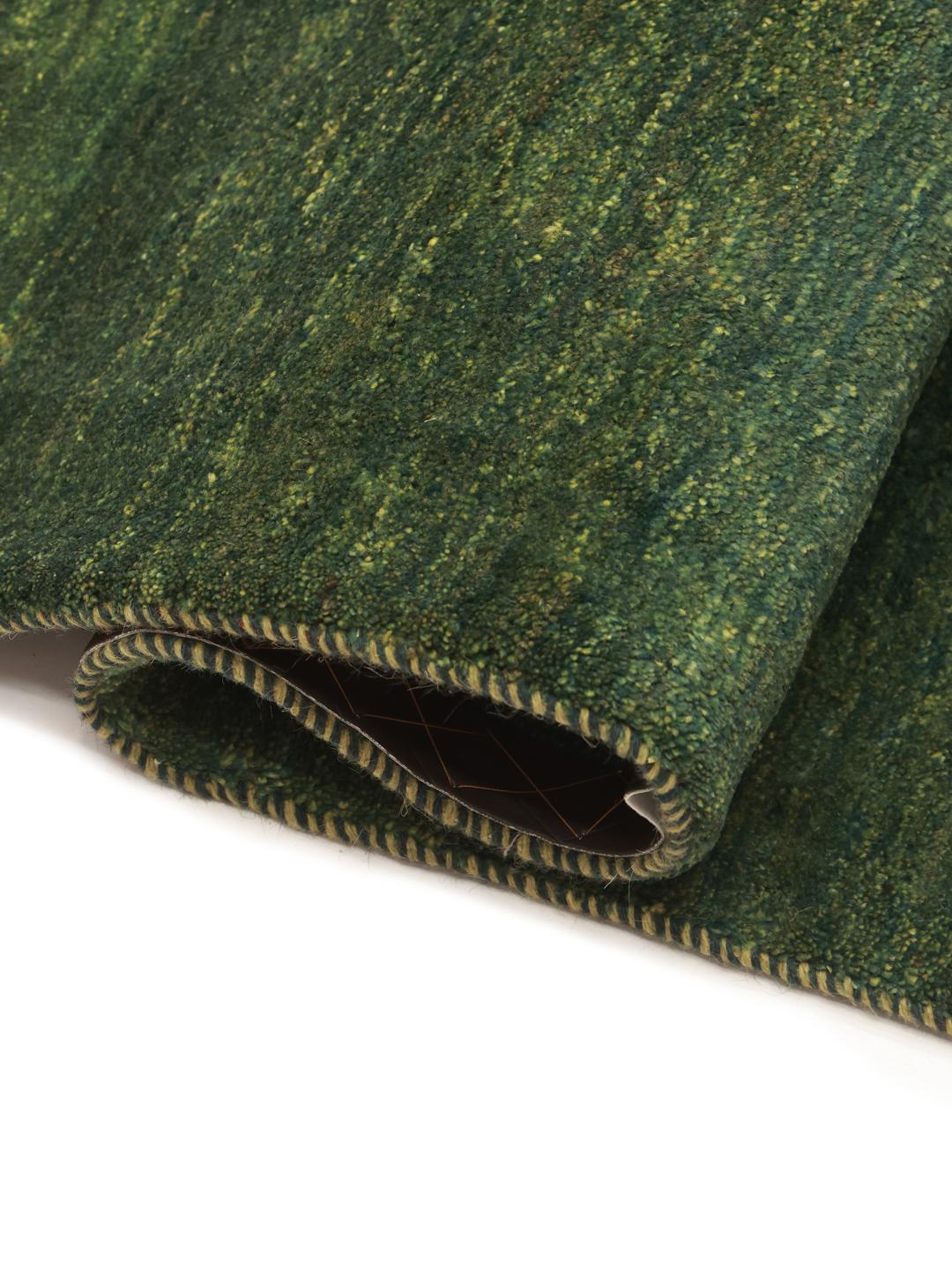 A hand-knotted Gabbeh rug from the Middle East in a deep, variegated dark-green colour.