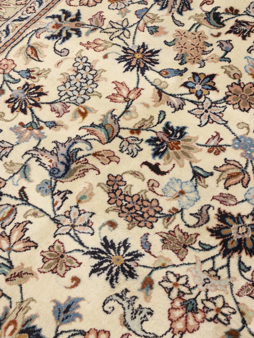 A hand-knotted Keshan rug from the Middle East with a beige field and floral patterns.