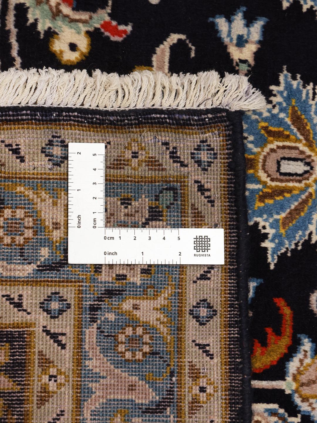 A large, rectangular hand-knotted Keshan rug from the Middle East featuring a floral pattern in dark-blue and cream tones.