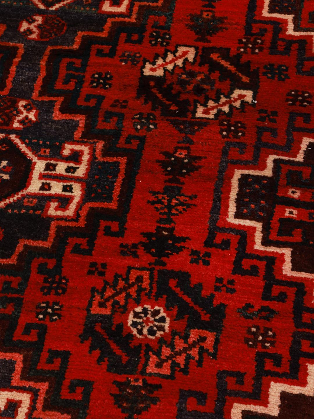 A hand-knotted Shiraz rug from the Middle East featuring a vibrant red field and bold geometric medallion patterns.