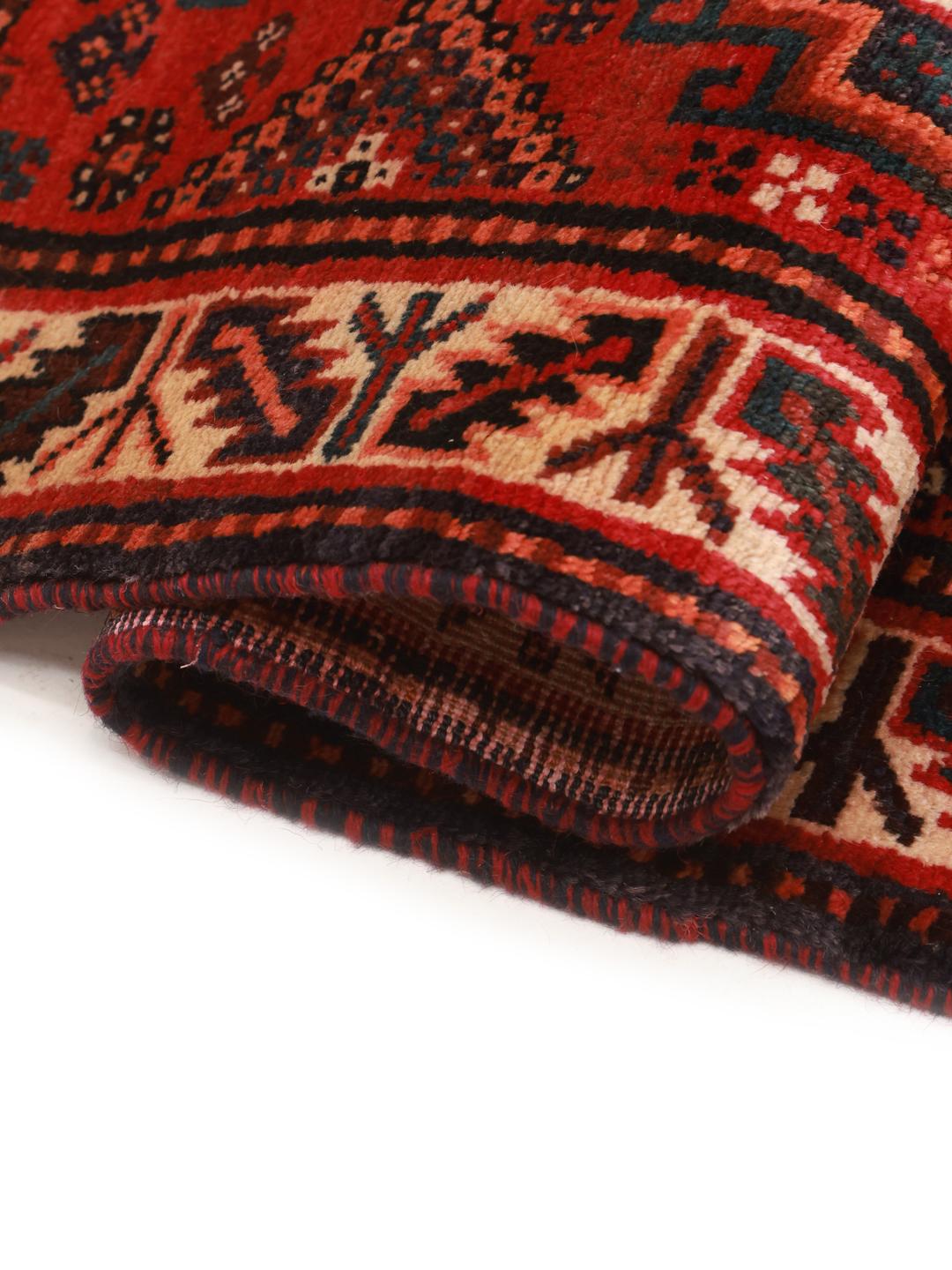 A hand-knotted Shiraz rug from the Middle East featuring a vibrant red field and bold geometric medallion patterns.