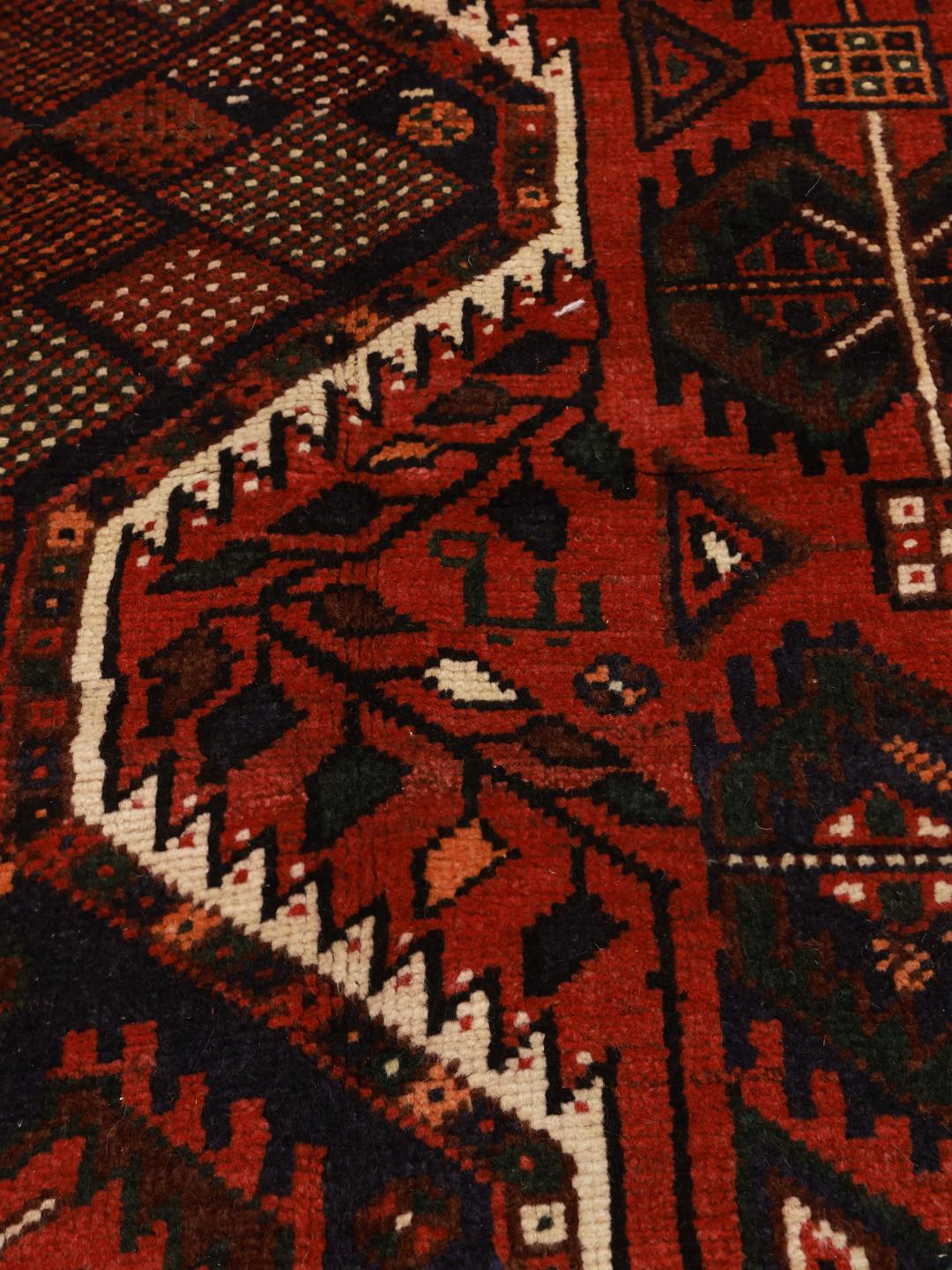 Hand-knotted Shiraz rug from the Middle East featuring a vibrant red field and tribal geometric patterns.