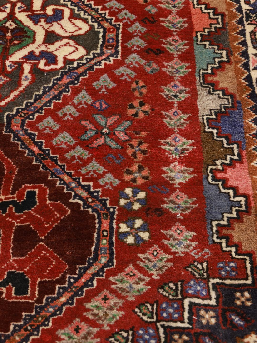 Hand-knotted red Ghashghai rug featuring tribal geometric motifs