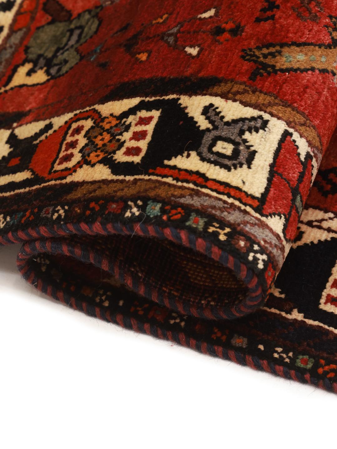 A unique hand-knotted Ghashghai rug from the Middle East with a vibrant red field and animal motifs.