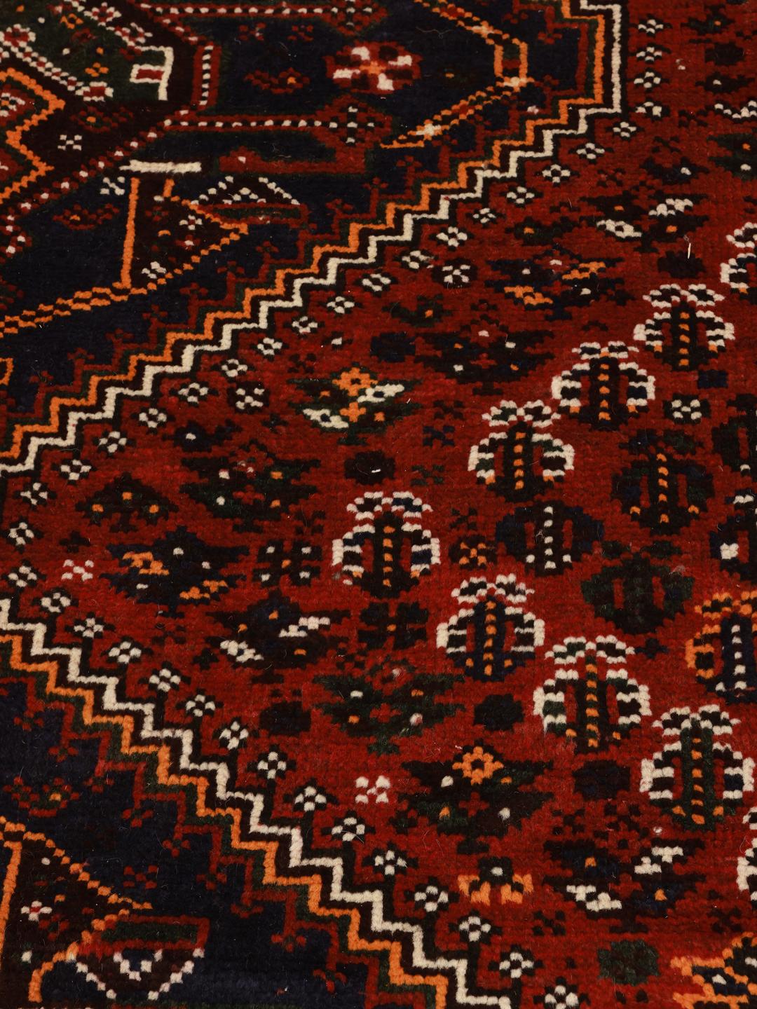 A hand-knotted Shiraz rug from the Middle East featuring a dark-red field with geometric medallions.