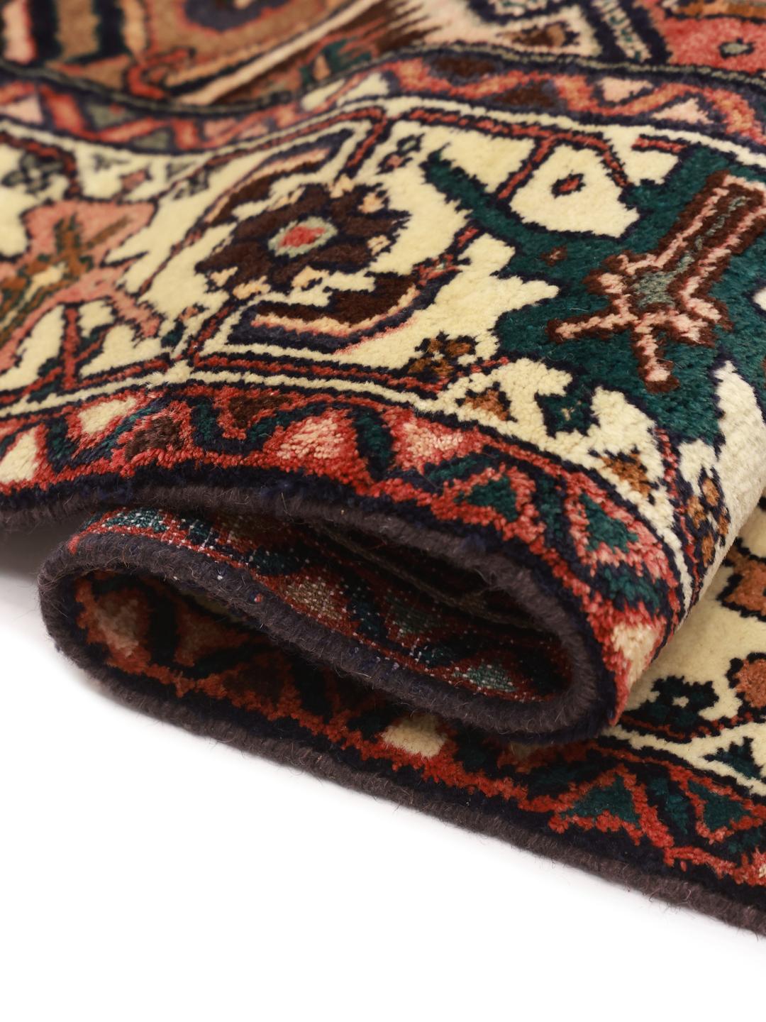 Een handgeknoopt Hosseinabad tapijt uit het Midden-Oosten met een rood veld en traditionele geometrische motieven.