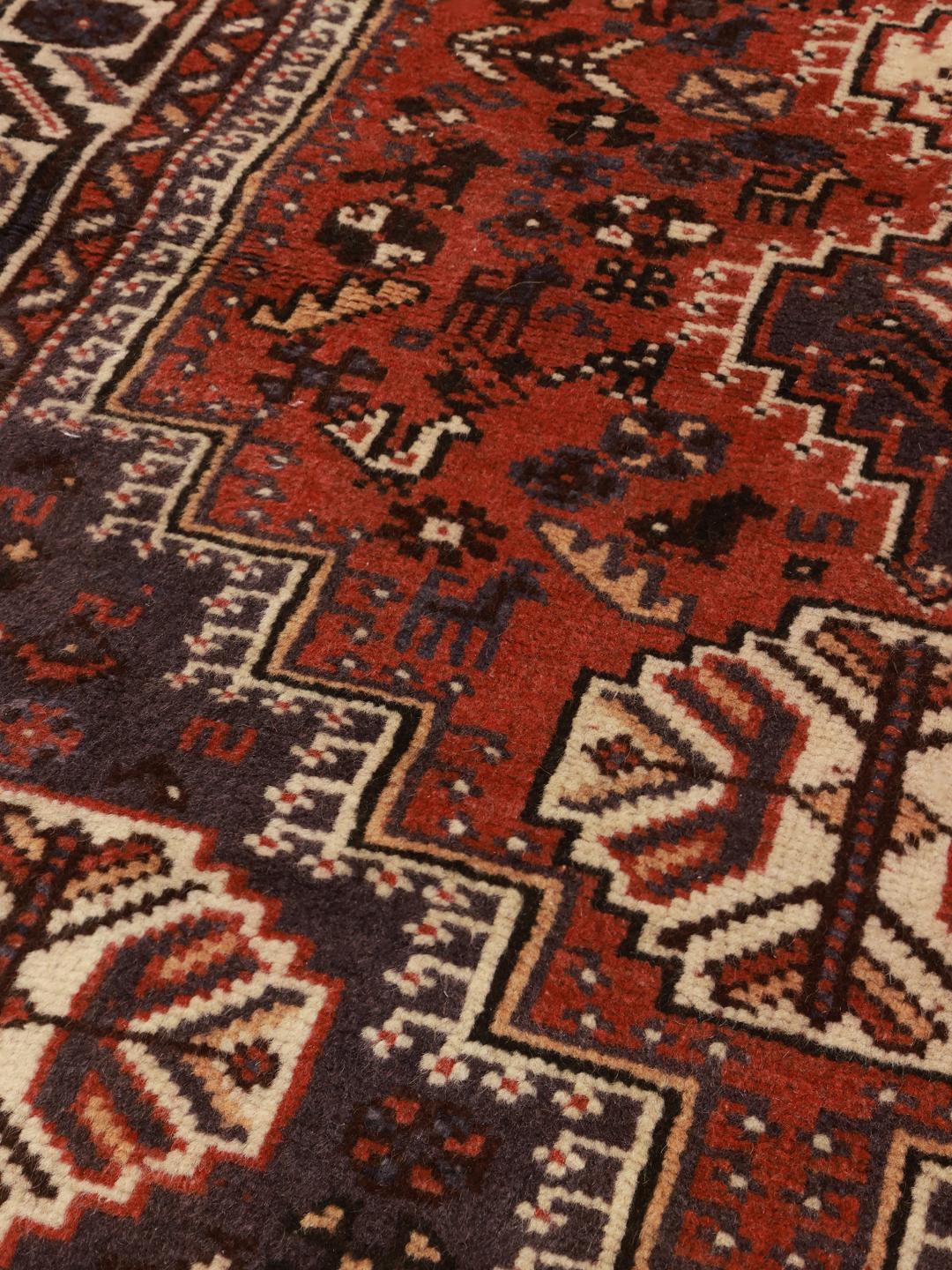 Et håndknyttet Shiraz-tæppe fra Mellemøsten med et levende rødt og mørkeblåt geometrisk mønster.