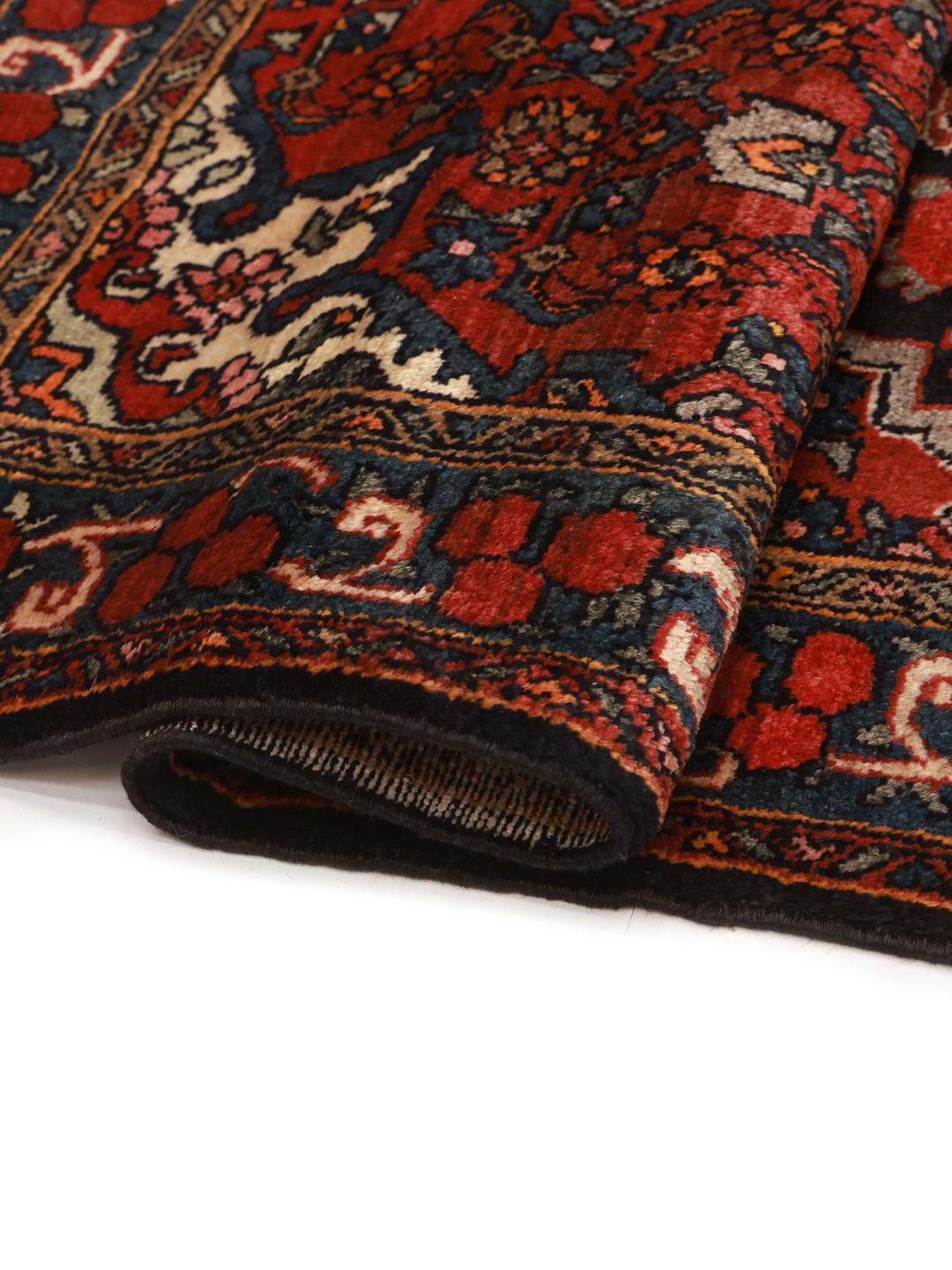 A hand-knotted Hosseinabad wool rug from the Middle East featuring a red field and central medallion.