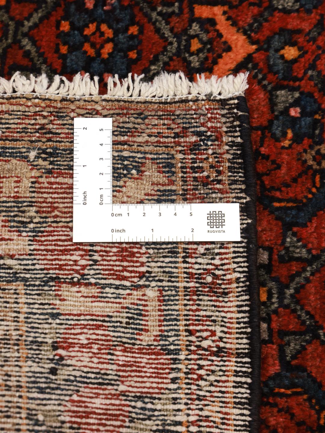 A hand-knotted Hosseinabad wool rug from the Middle East featuring a red field and central medallion.