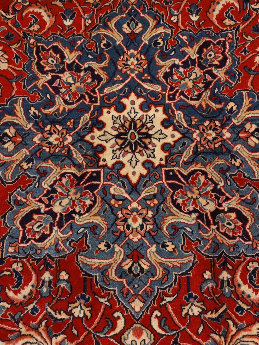 A beautiful, one-of-a-kind hand-knotted Sarough rug from the Middle East featuring a vibrant red field with intricate blue and cream floral motifs.