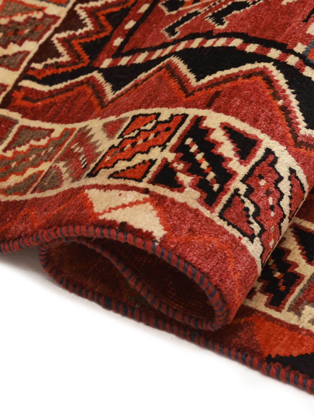 A hand-knotted Qashqai rug from the Middle East featuring a vibrant red field with geometric floral motifs.