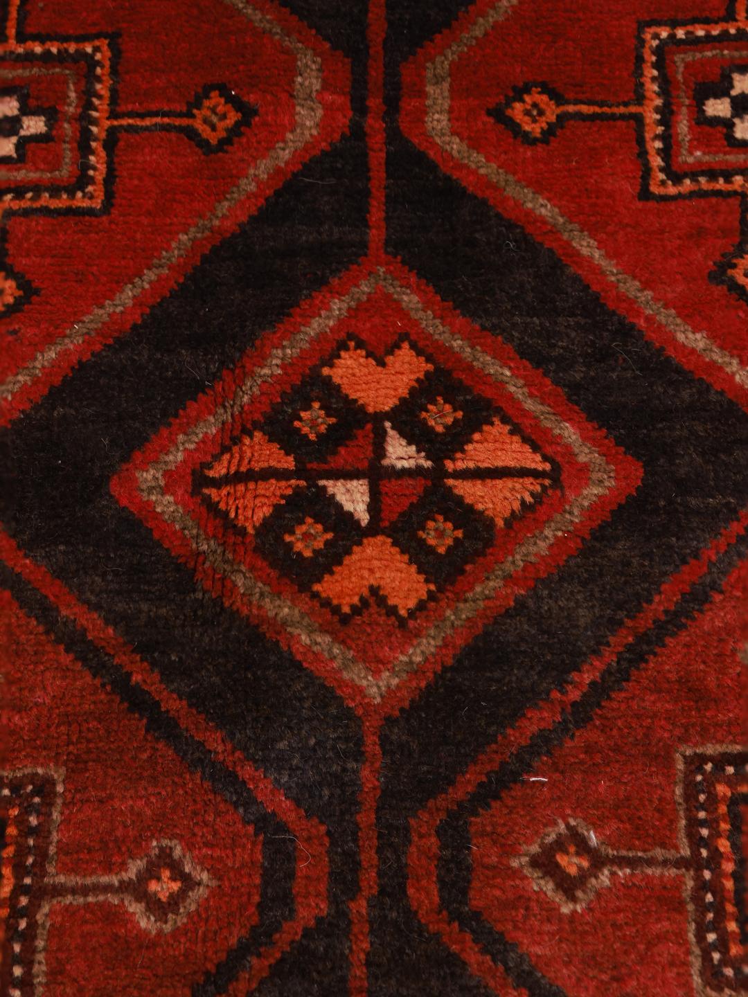 Et håndknyttet rødt og mørkt Shiraz-tæppe med geometriske diamantmotiver fra Mellemøsten.