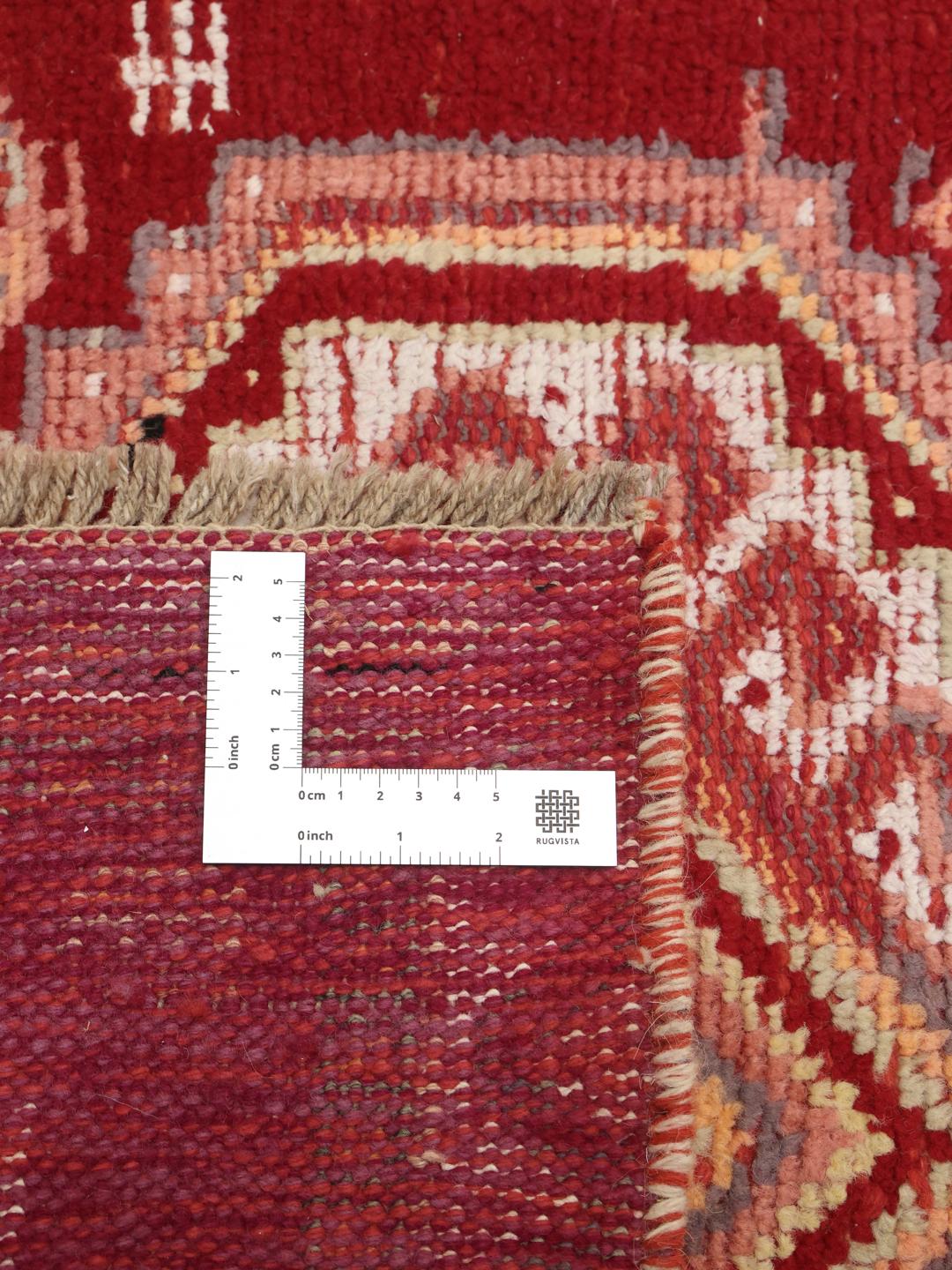 Een unieke handgeknoopte loper uit het Midden-Oosten met een rode achtergrond en geometrische diamantpatronen.