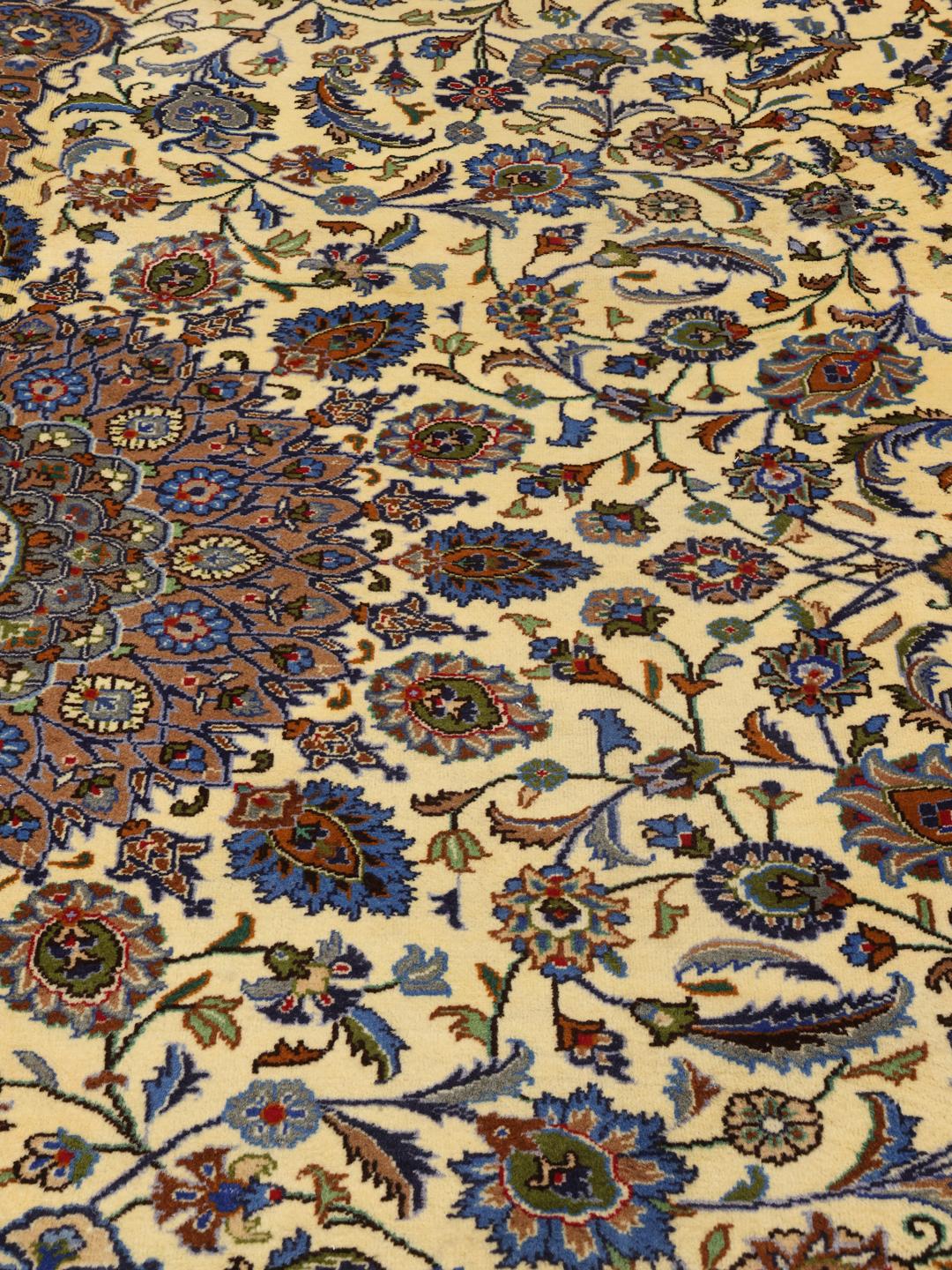A large hand-knotted beige Mashad rug from the Middle East with intricate floral patterns.
