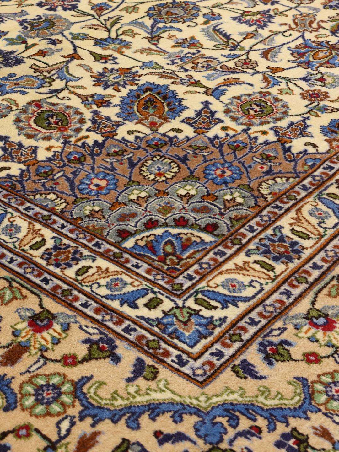 A large hand-knotted beige Mashad rug from the Middle East with intricate floral patterns.