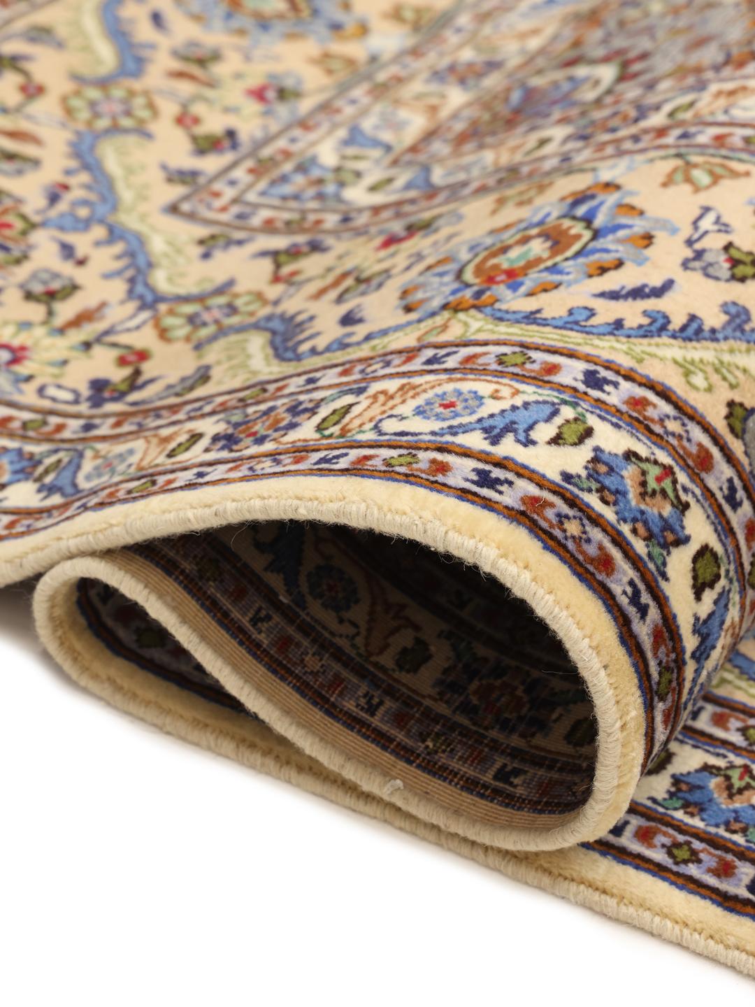 A large hand-knotted beige Mashad rug from the Middle East with intricate floral patterns.