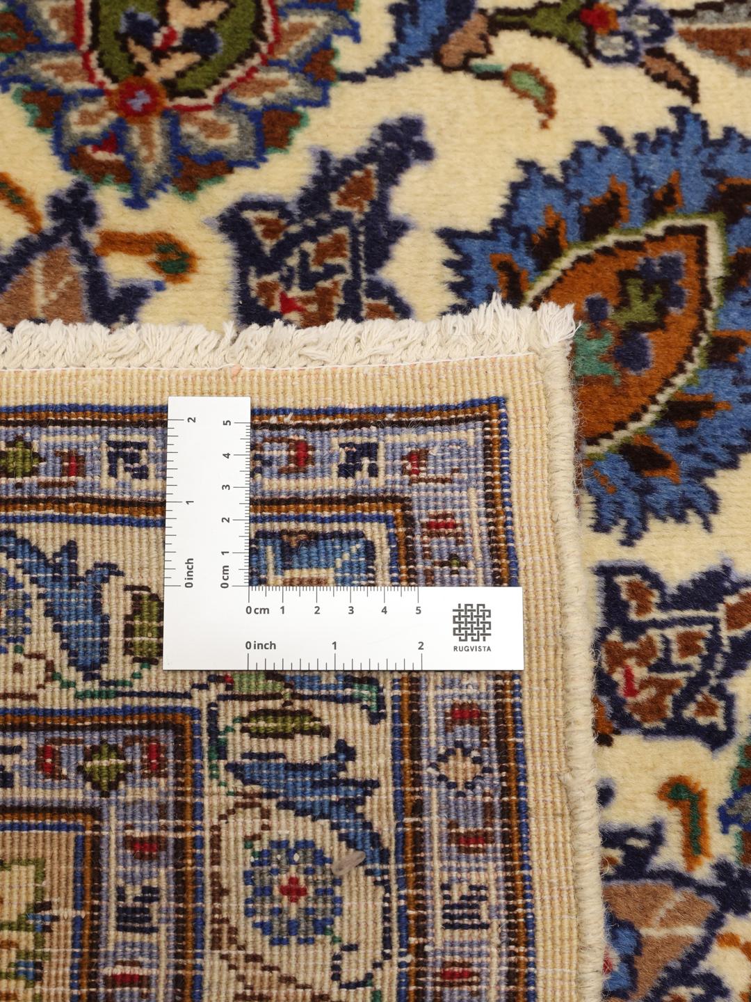 A large hand-knotted beige Mashad rug from the Middle East with intricate floral patterns.