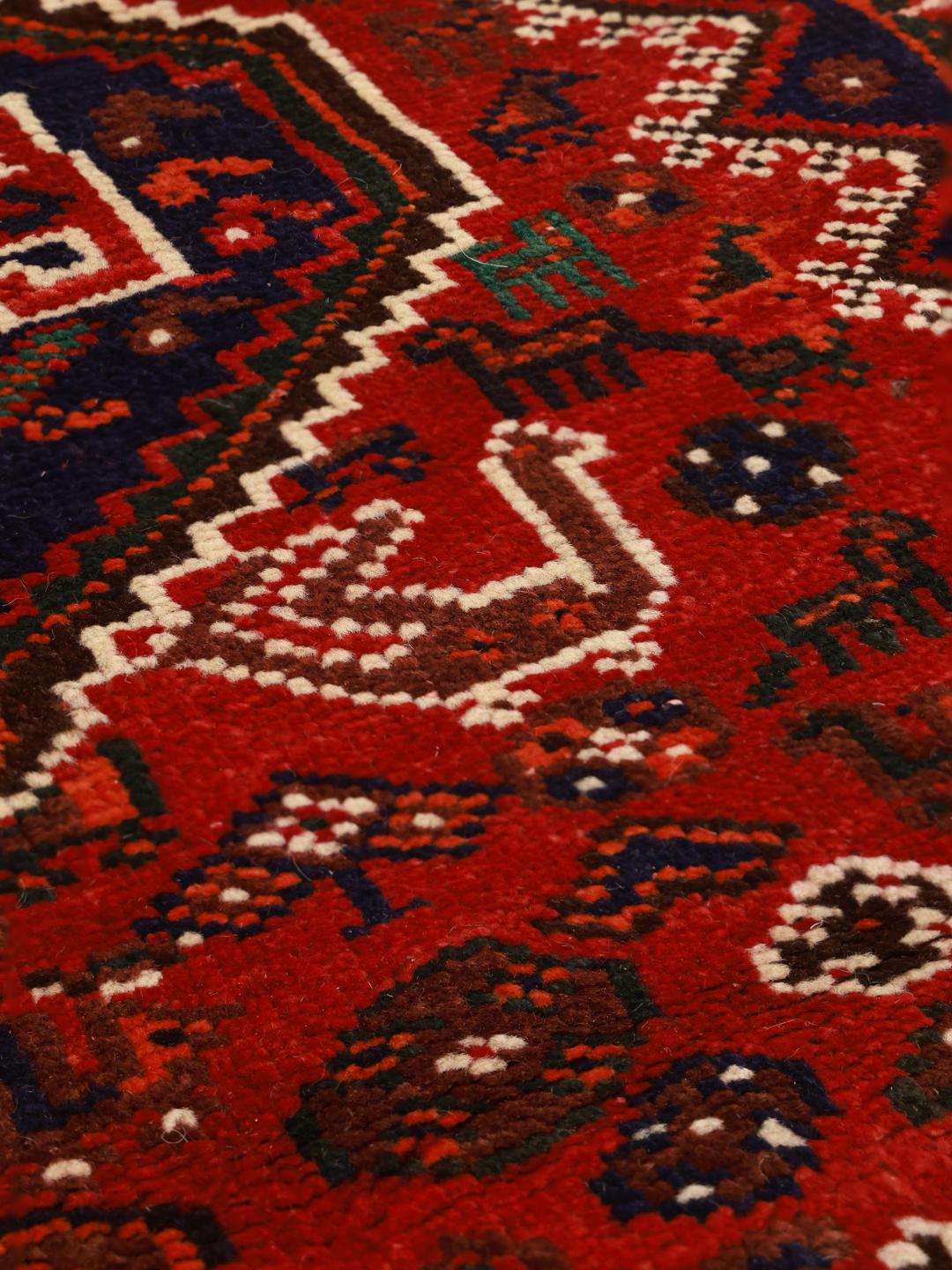 Hand-knotted Shiraz rug from the Middle East featuring a vibrant red field and tribal motifs