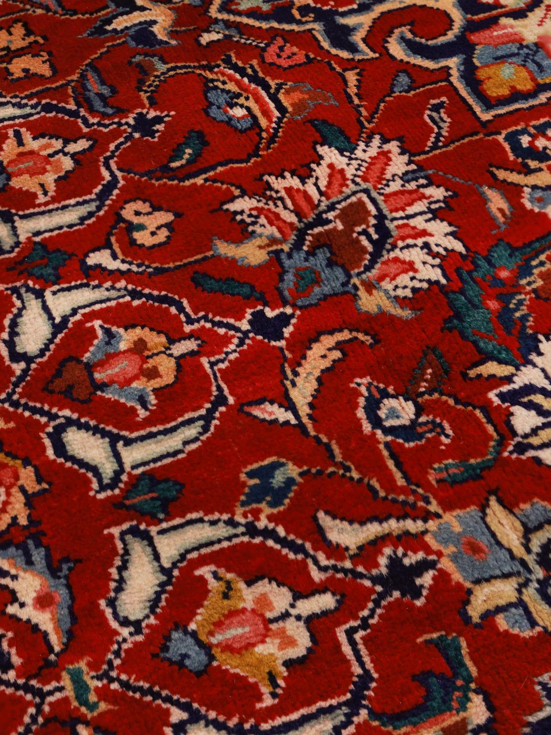 A hand-knotted Sarough rug from the Middle East featuring a vibrant red field with intricate floral patterns.