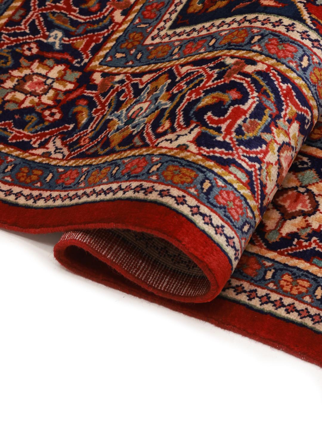 A hand-knotted Sarough rug from the Middle East featuring a vibrant red field with intricate floral patterns.