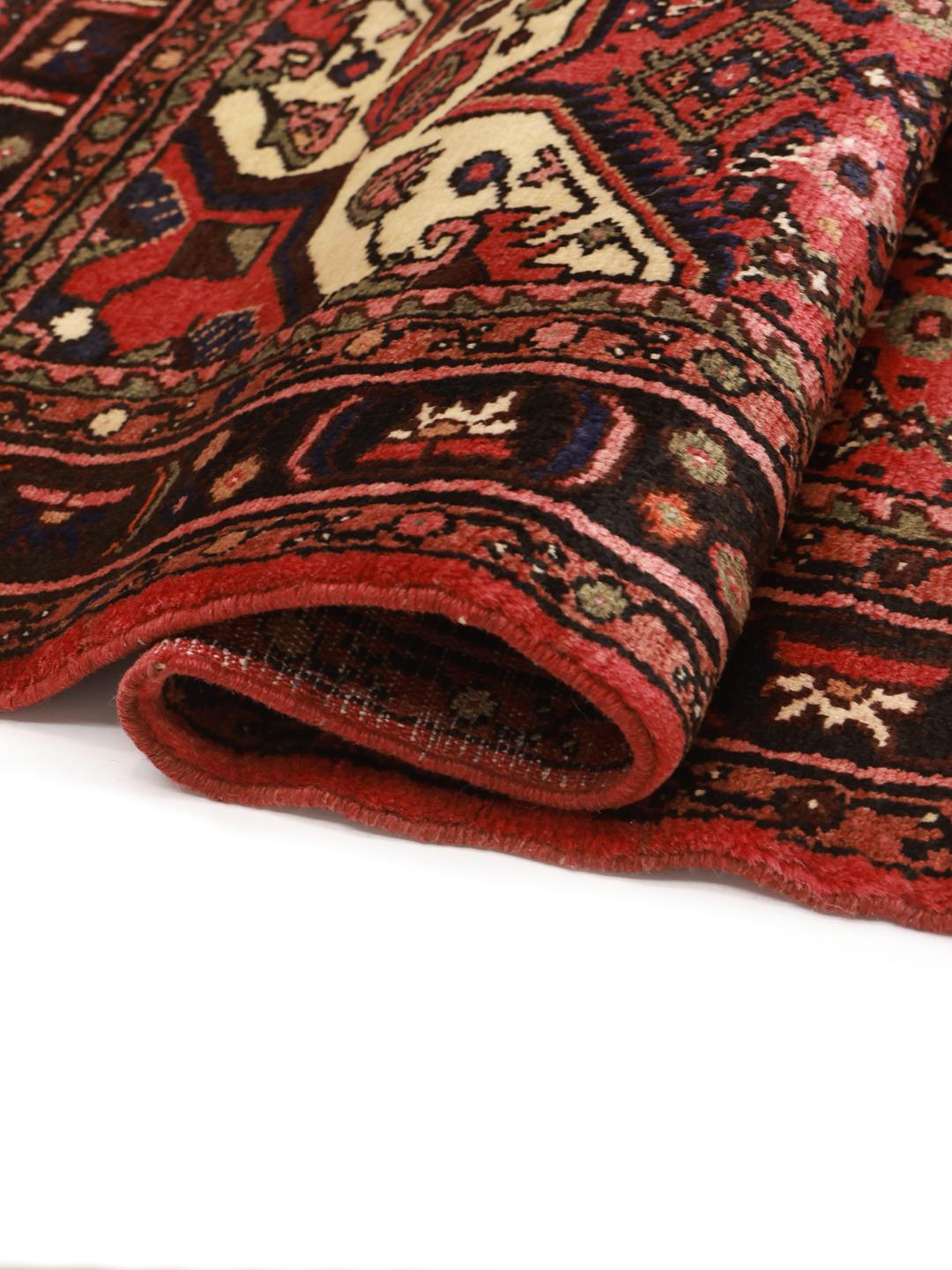 A hand-knotted Hosseinabad rug from the Middle East in deep red and dark blue tones.