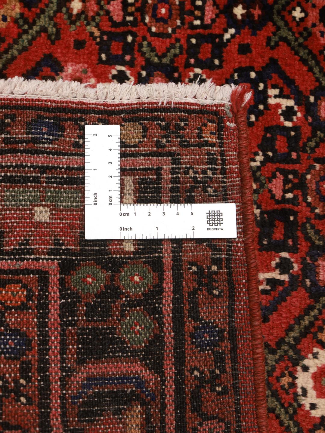 A hand-knotted Hosseinabad rug from the Middle East in deep red and dark blue tones.
