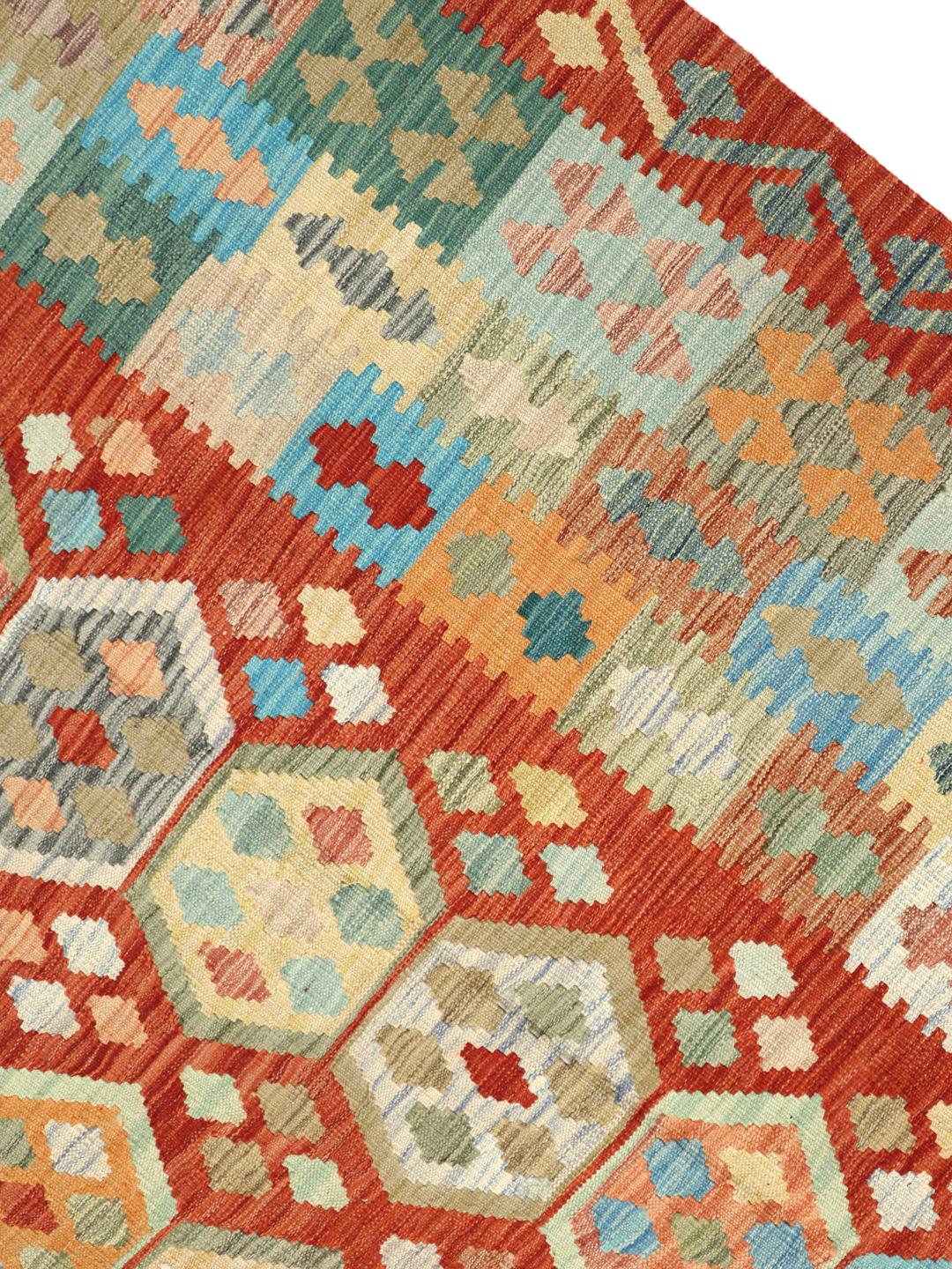 Een groot rechthoekig handgeweven Afghaans kelim tapijt met een levendig rood veld en geometrische zeshoekige patronen.
