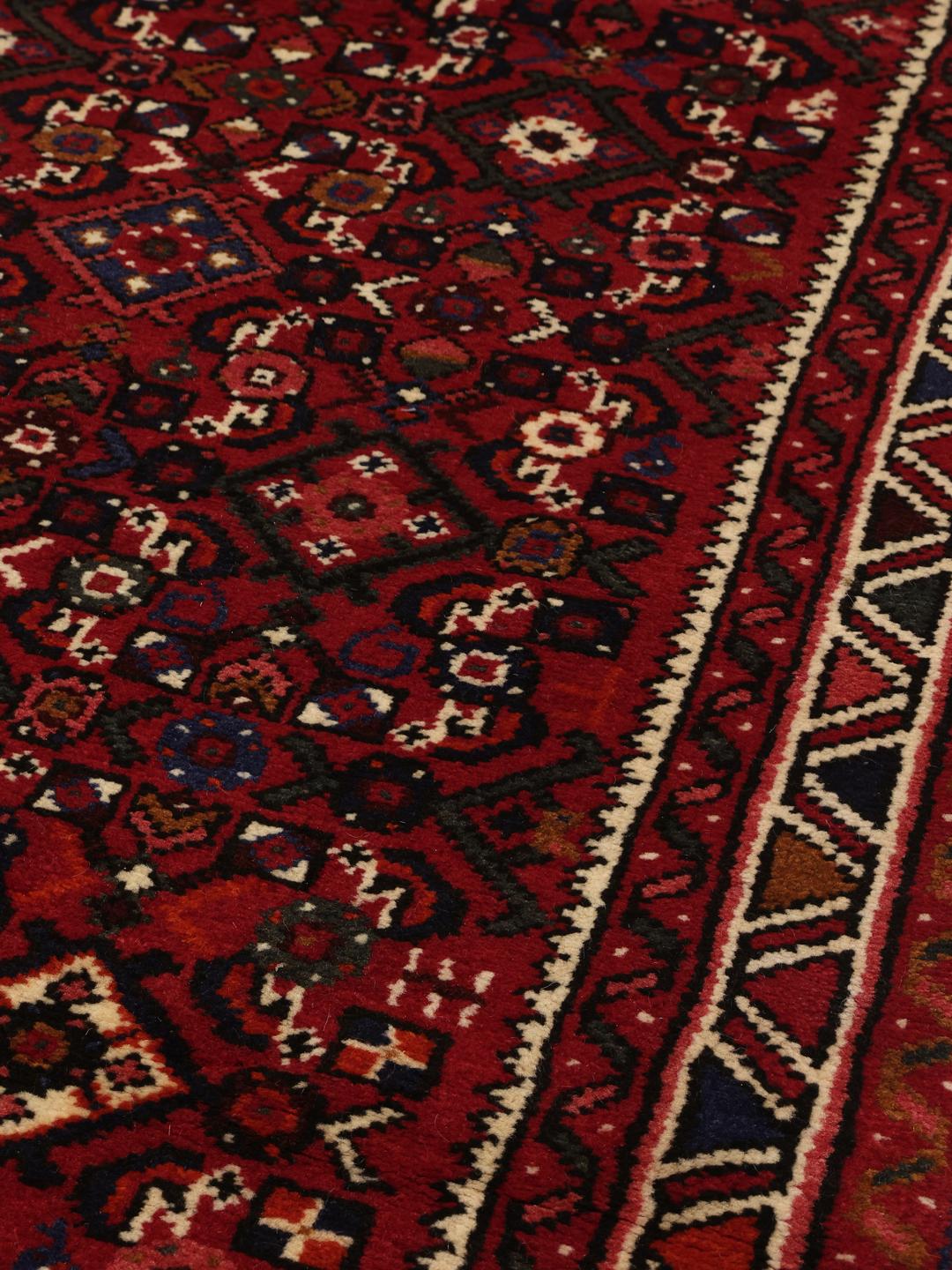 Un long tapis couloir Hosseinabad noué à la main en provenance du Moyen-Orient dans des tons rouge foncé.