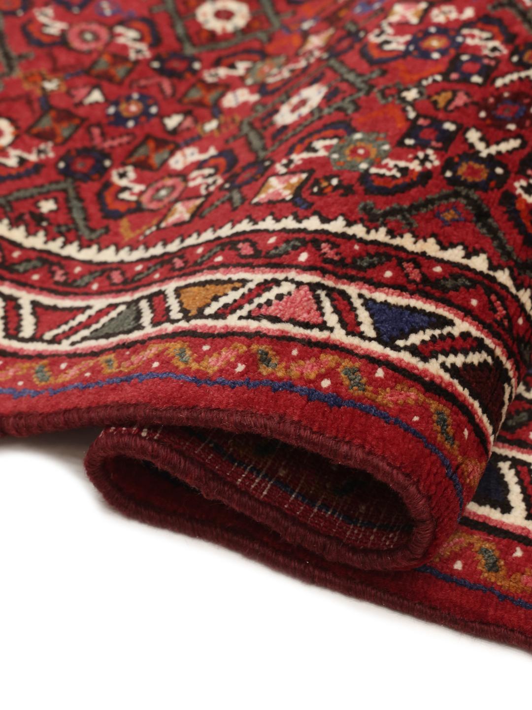 Un long tapis couloir Hosseinabad noué à la main en provenance du Moyen-Orient dans des tons rouge foncé.