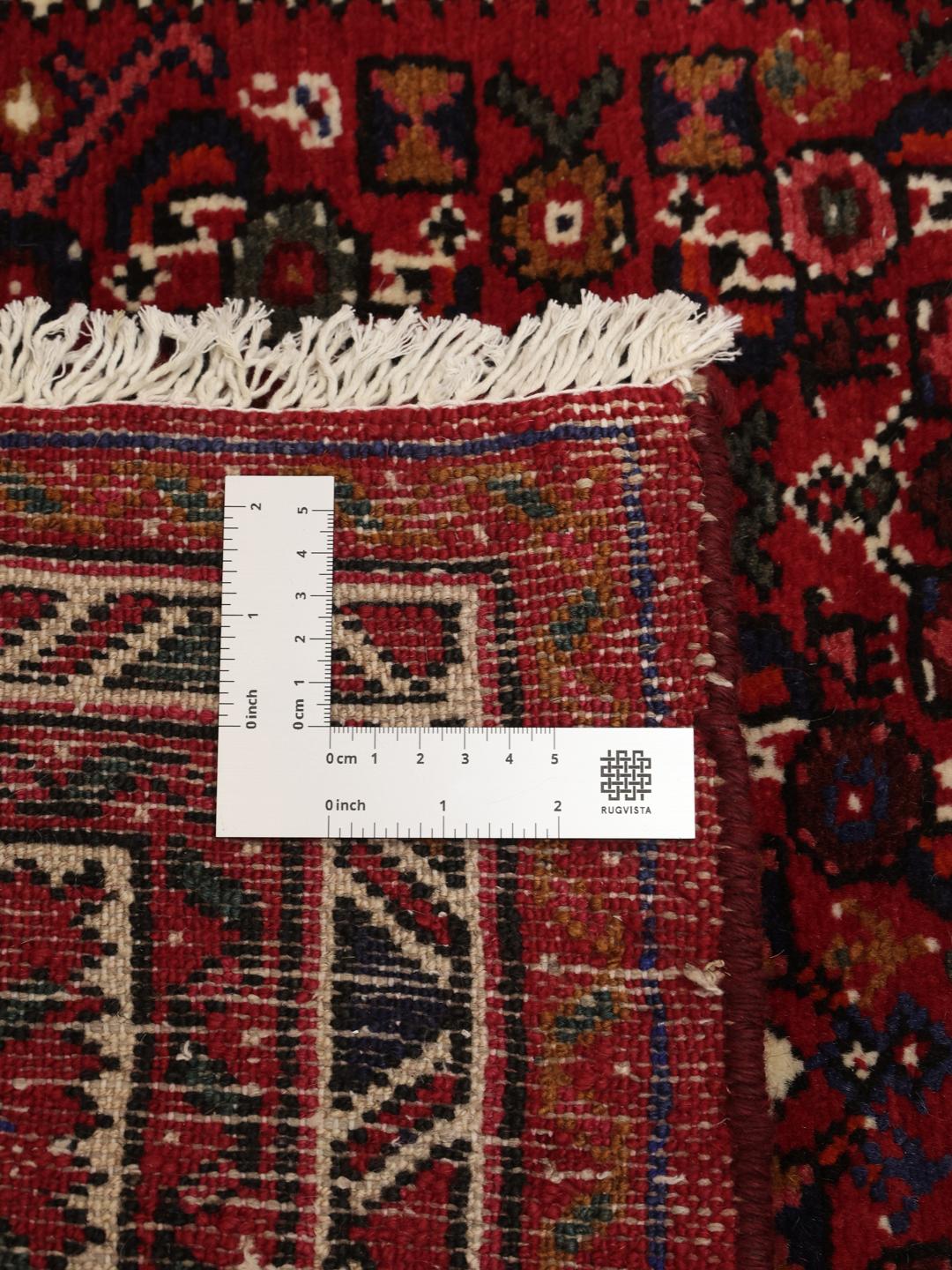 Un long tapis couloir Hosseinabad noué à la main en provenance du Moyen-Orient dans des tons rouge foncé.