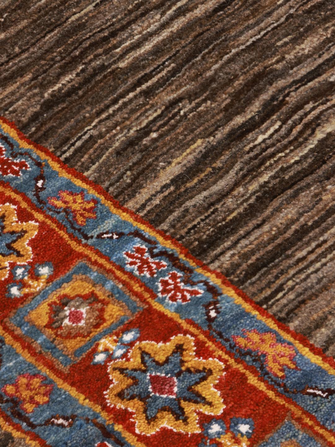 A rectangular Gabbeh rug from the Middle East with a brown field and vibrant border.