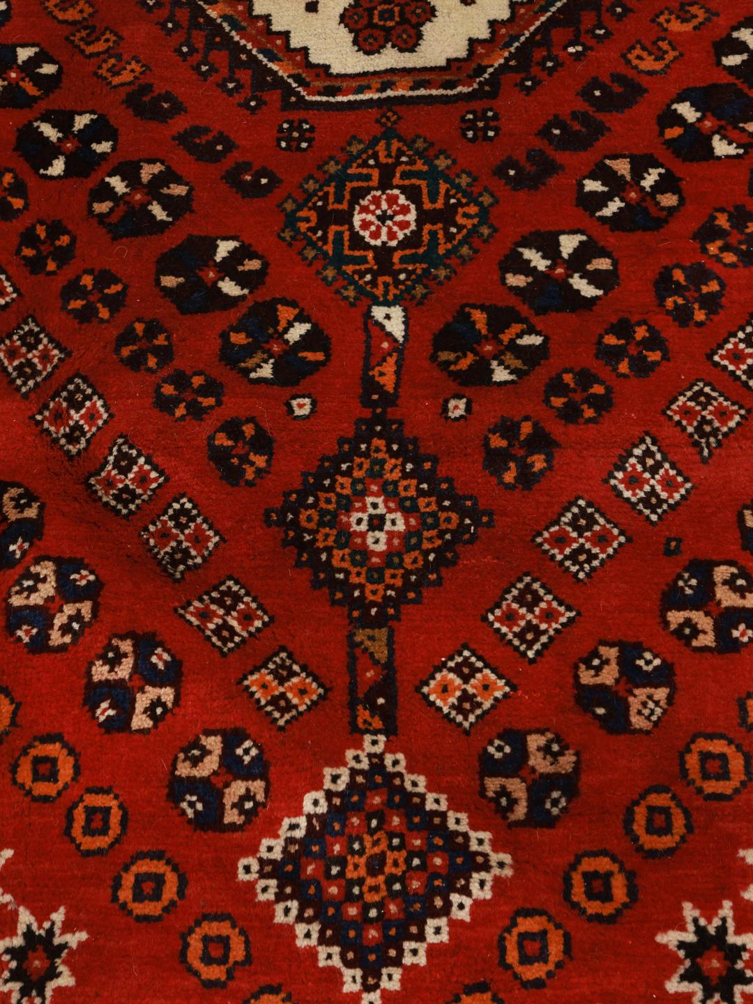 Hand-knotted Qashqai rug from the Middle East featuring a dark-red field and geometric patterns.