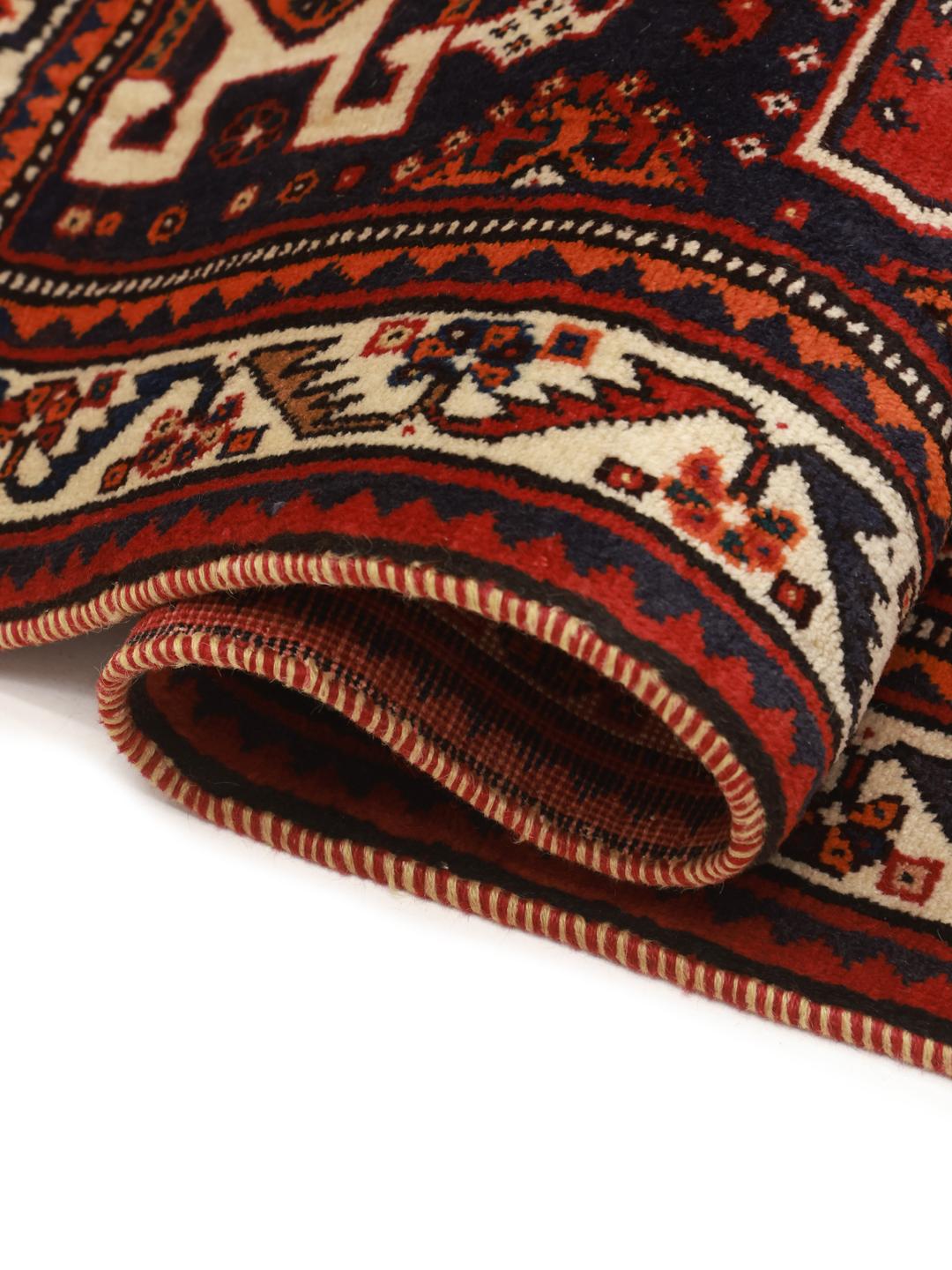 Hand-knotted Qashqai rug from the Middle East featuring a dark-red field and geometric patterns.
