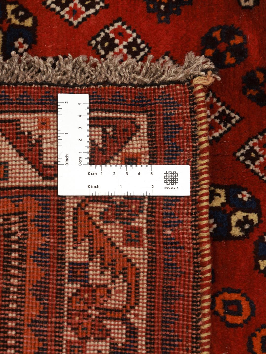 Hand-knotted Qashqai rug from the Middle East featuring a dark-red field and geometric patterns.