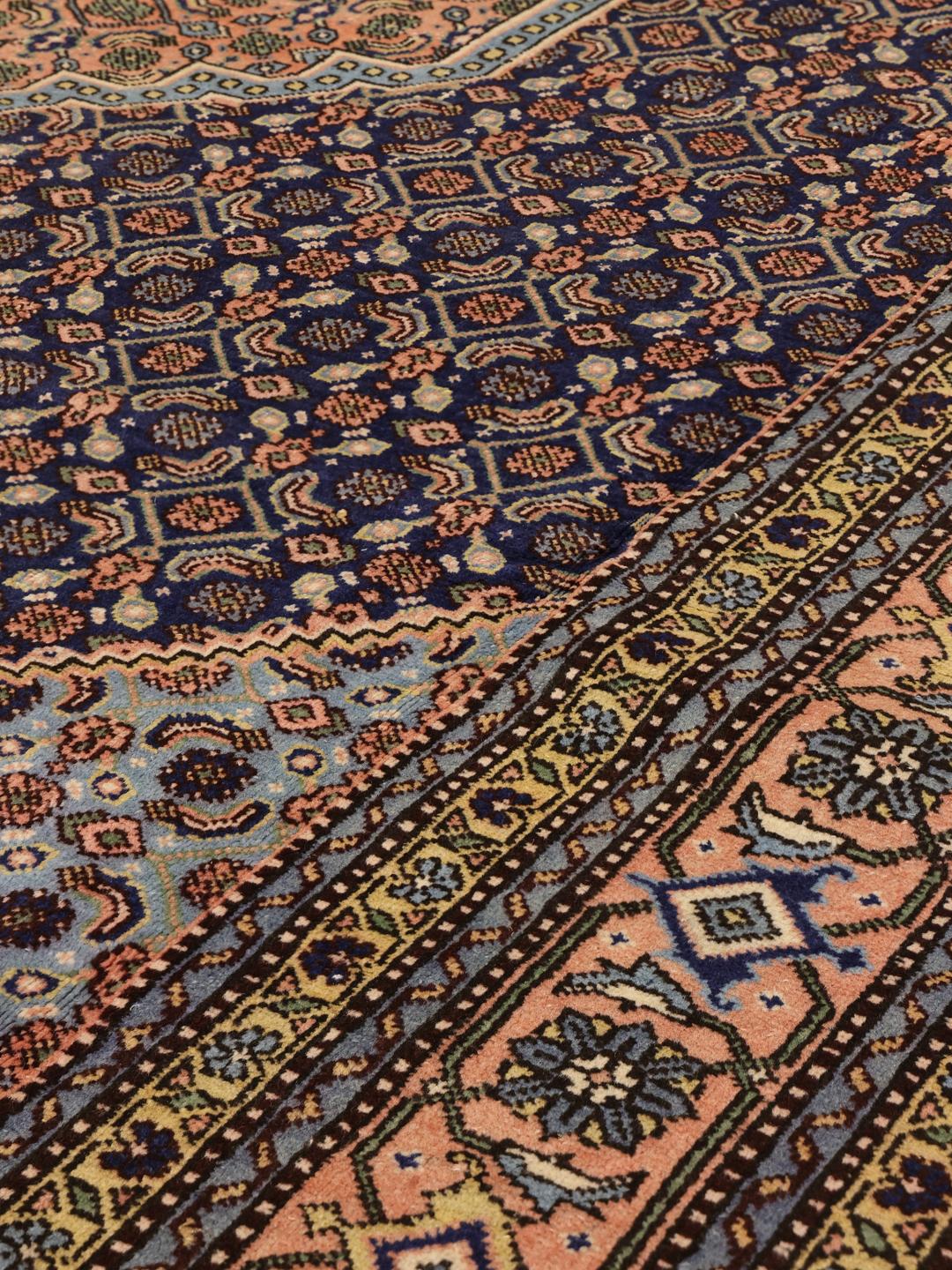 Een rechthoekig Ardebil-tapijt uit het Midden-Oosten met een donkerblauw veld en bloemmotieven