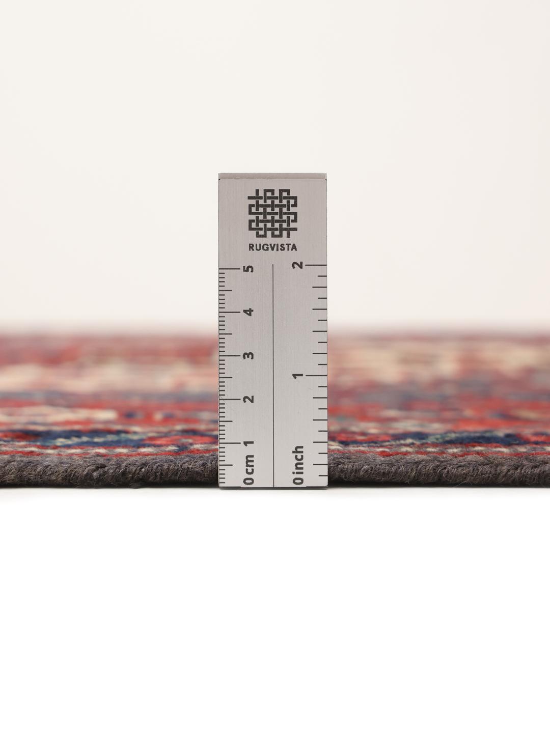 Et håndknyttet Senneh-tæppe fra Mellemøsten med et mørkerødt og blåt medaljondesign.