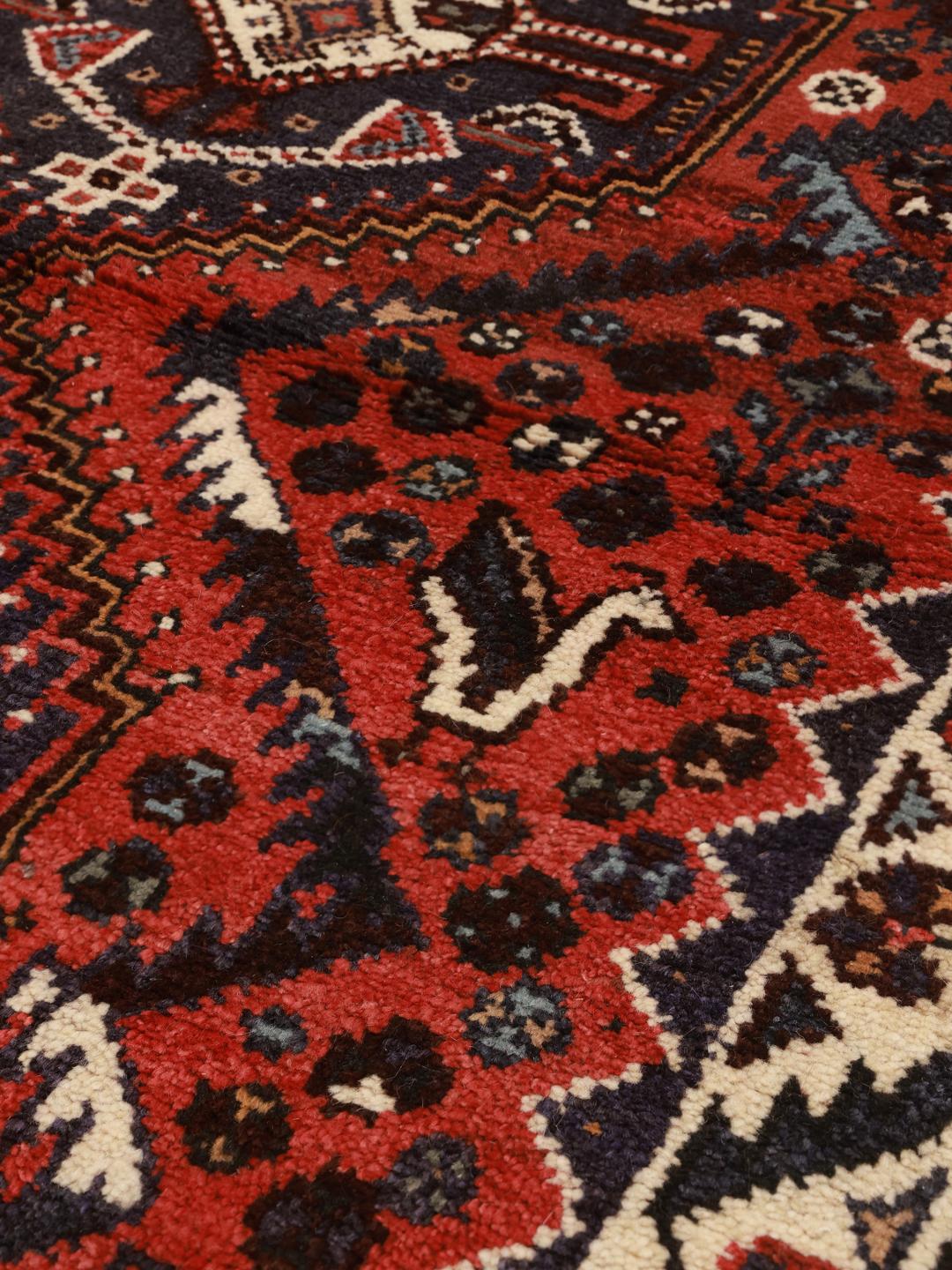 Hand-knotted Shiraz rug from the Middle East featuring a vibrant red field and geometric patterns.