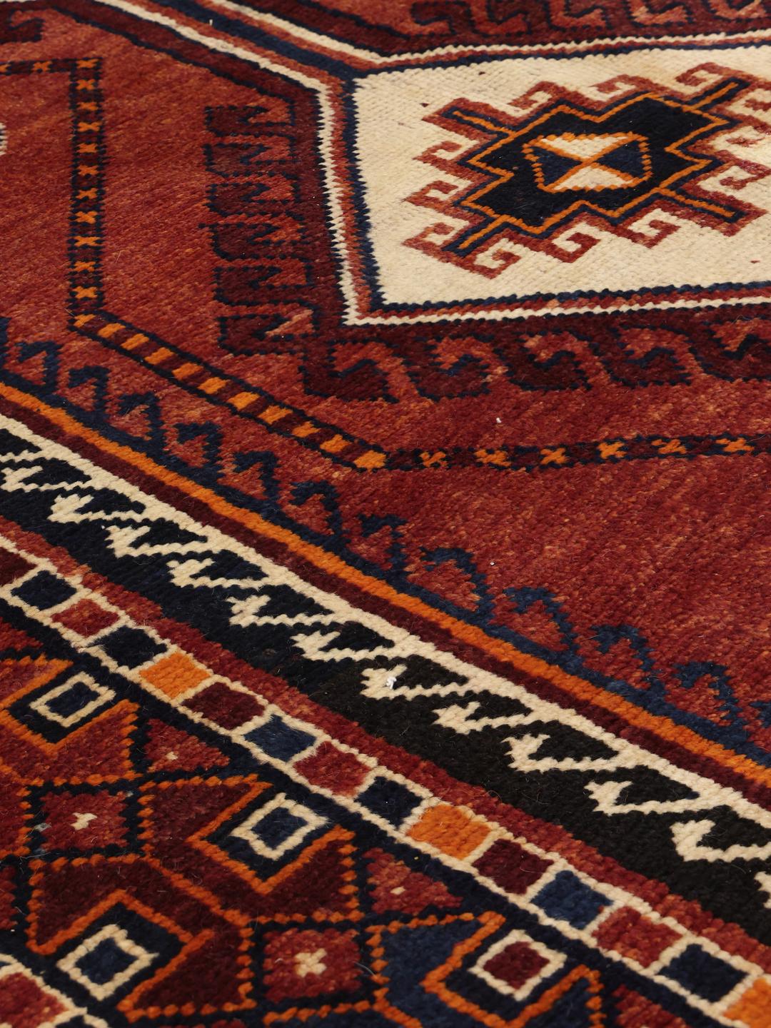 A hand-knotted Shiraz rug from the Middle East featuring a red and black geometric design.
