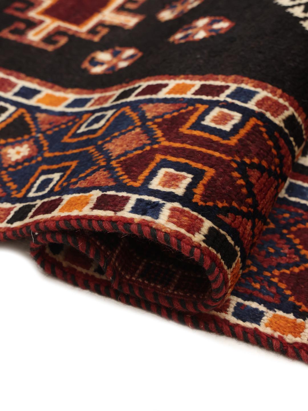 A hand-knotted Shiraz rug from the Middle East featuring a red and black geometric design.