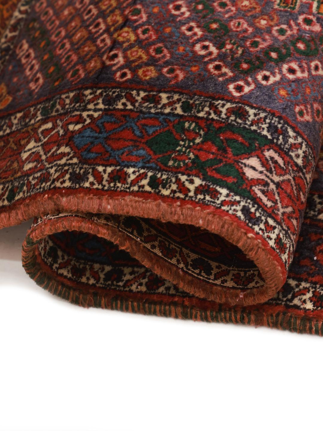 A hand-knotted Shahrbabak rug from the Middle East in deep red and blue tones.