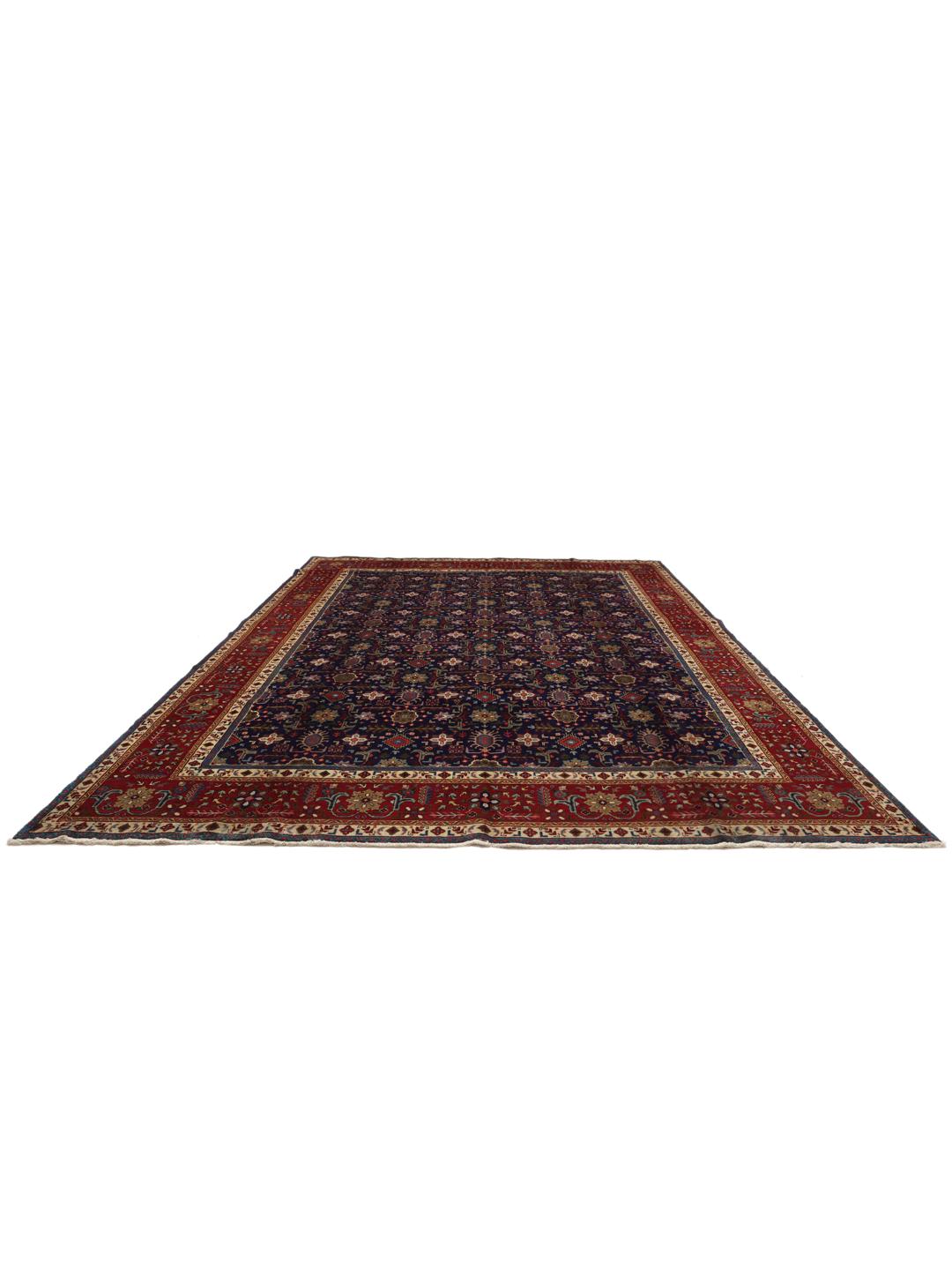 A large rectangular Tabriz rug from the Middle East featuring a dark-blue field and dark-red borders.
