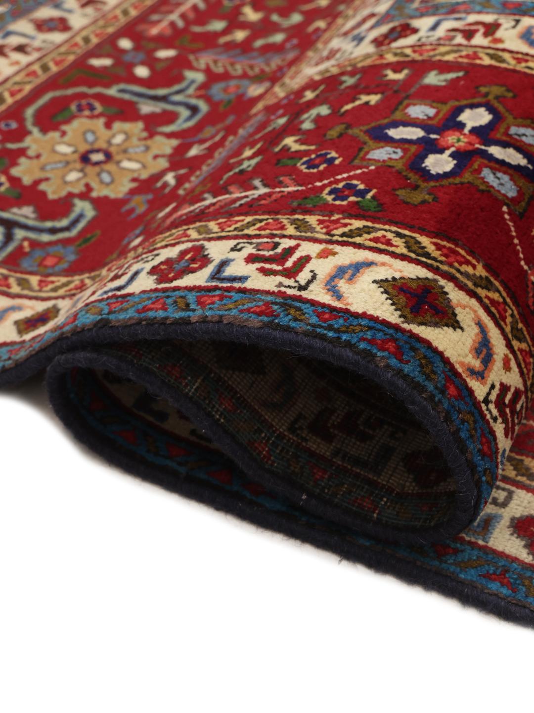 A large rectangular Tabriz rug from the Middle East featuring a dark-blue field and dark-red borders.
