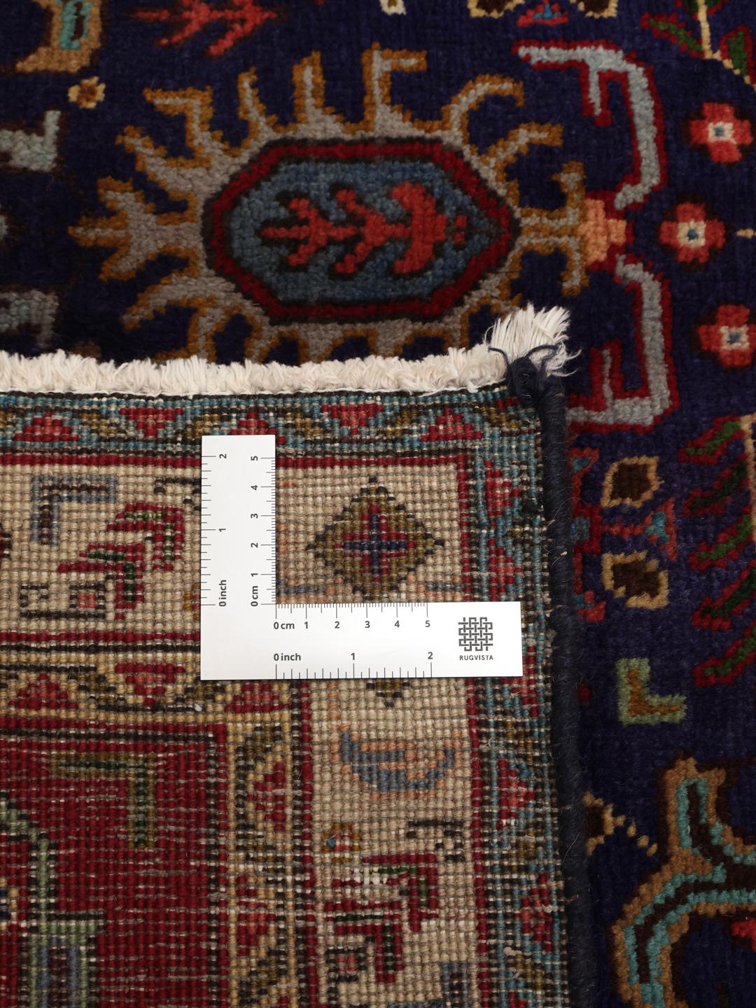 A large rectangular Tabriz rug from the Middle East featuring a dark-blue field and dark-red borders.