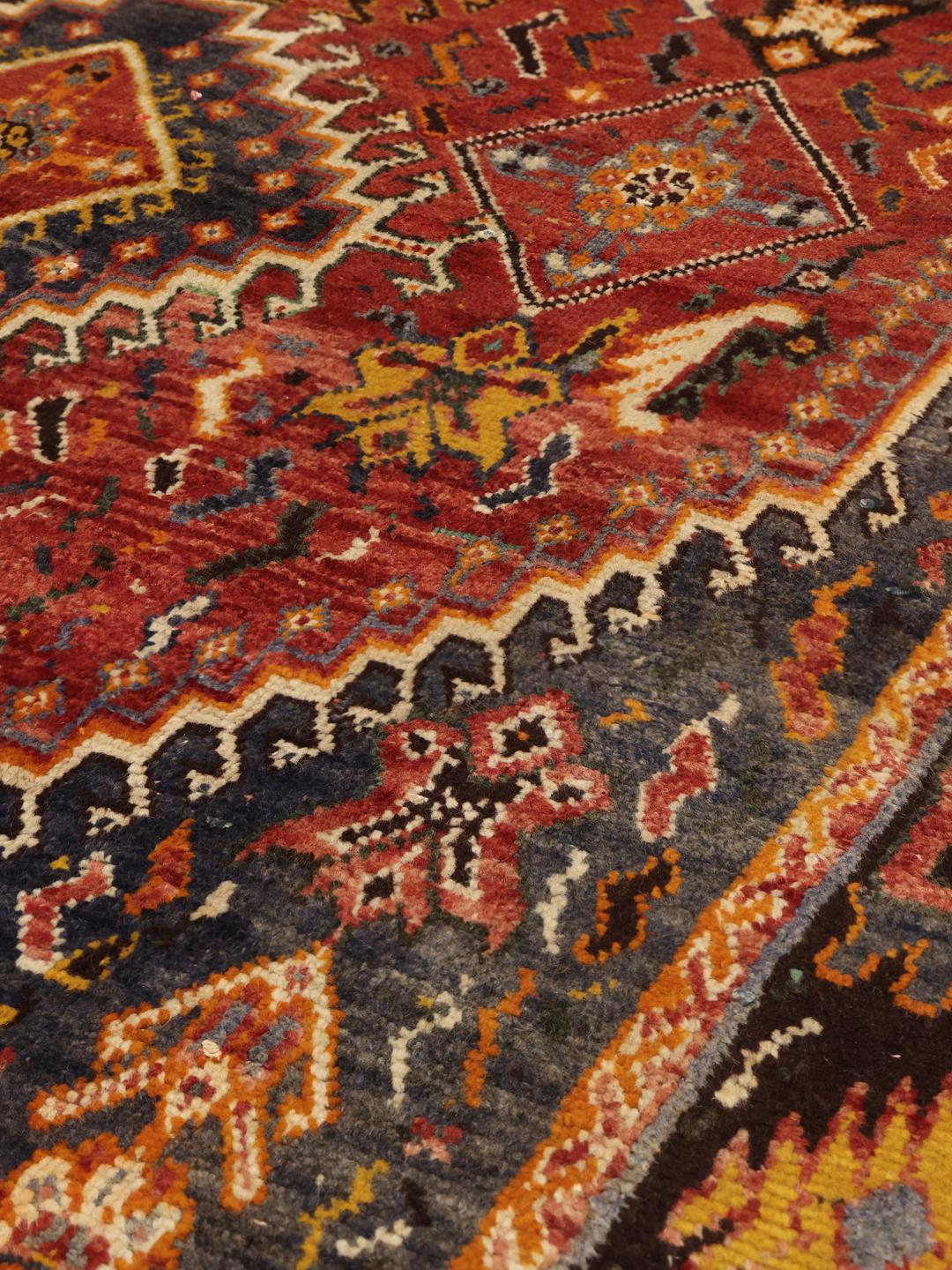 Handgeknoopt tapijt uit het Midden-Oosten in dieprode en blauwe tinten met traditionele geometrische patronen.