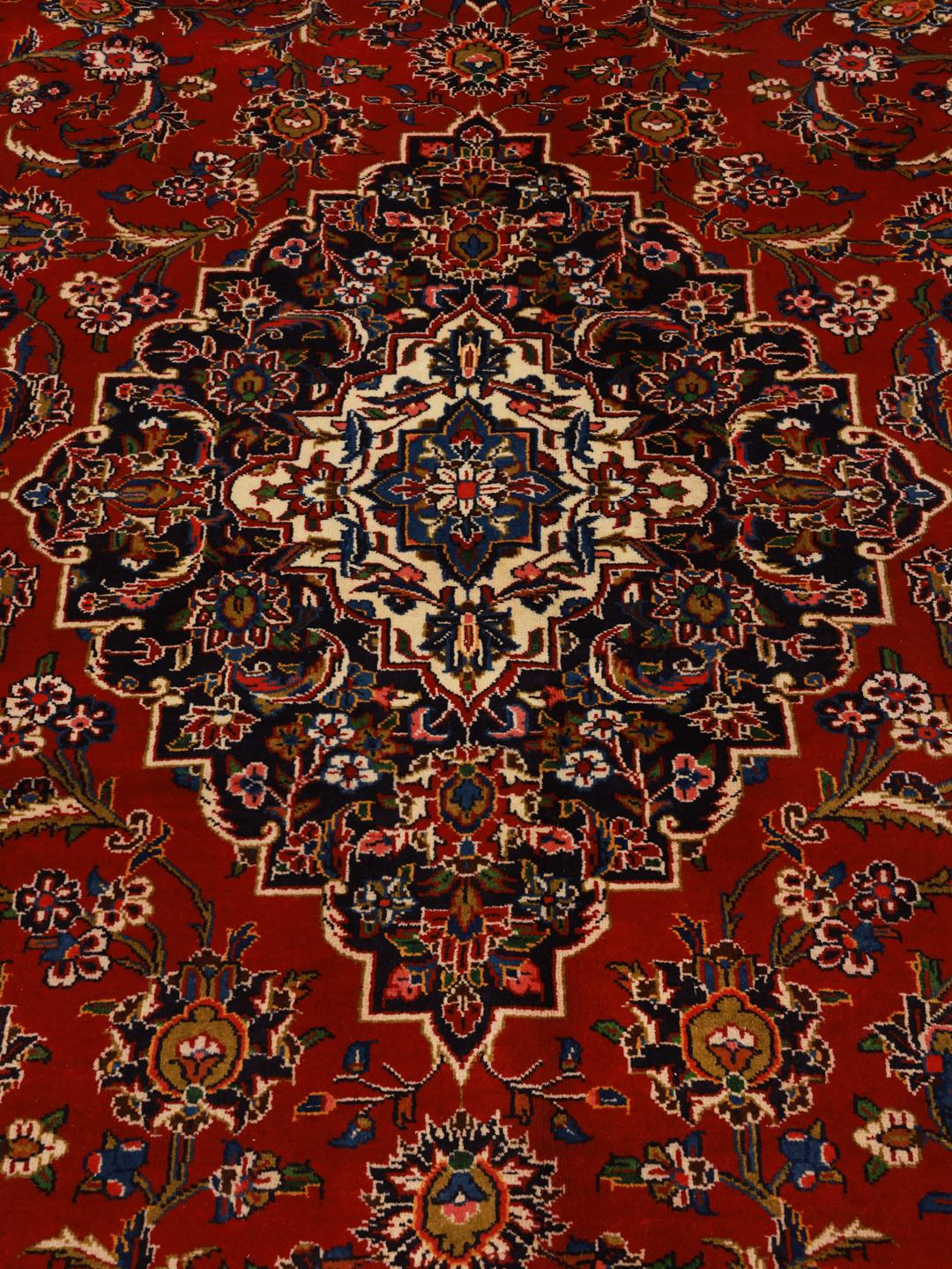 Hand-knotted Keshan rug from the Middle East with a red field and traditional floral medallion.
