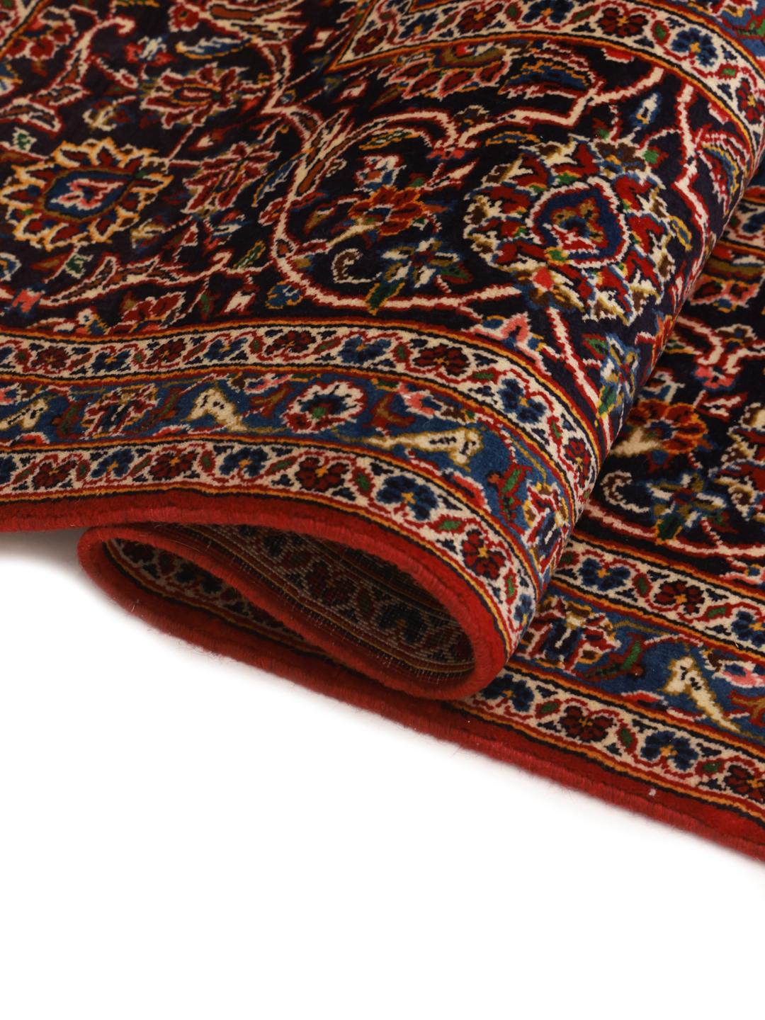 Hand-knotted Keshan rug from the Middle East with a red field and traditional floral medallion.